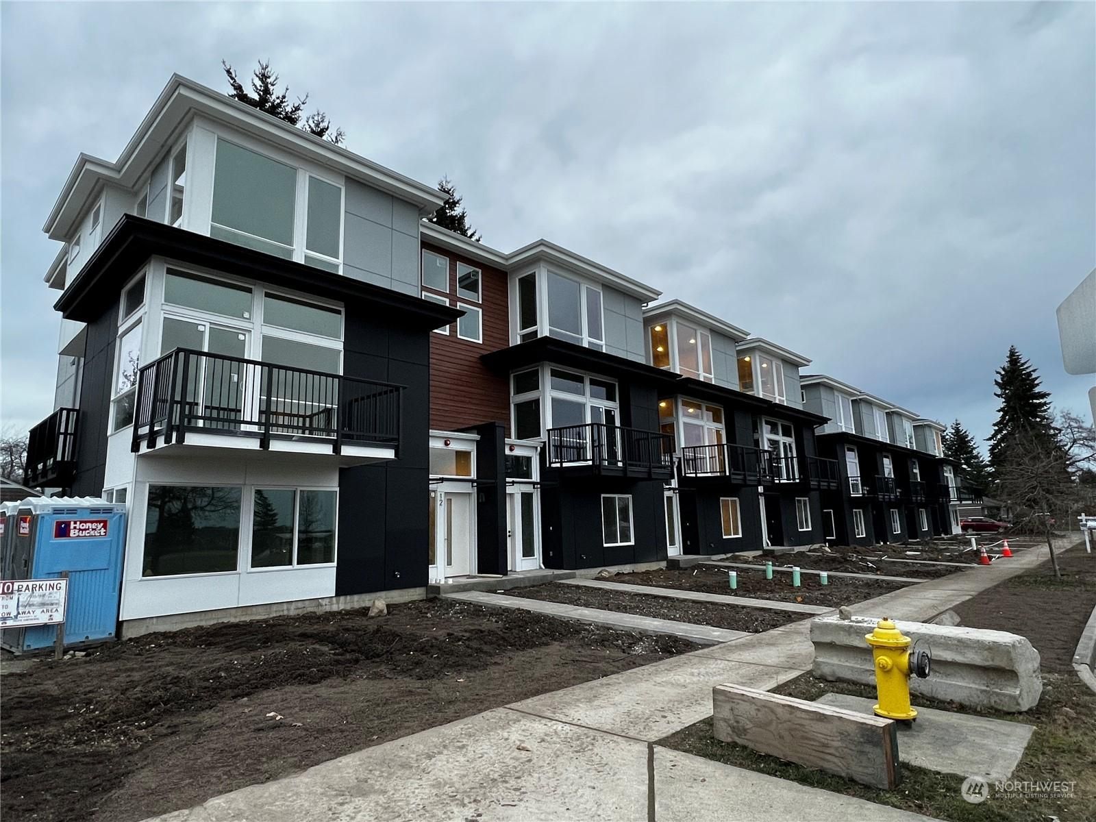 A large apartment building under construction with a fire hydrant in front of it.