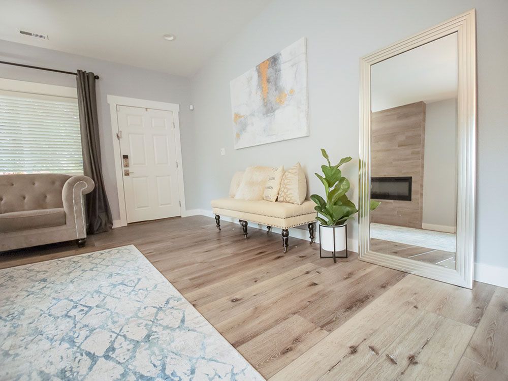 Bright modern living room with beige sofa, large mirror, abstract wall art, and gray rug