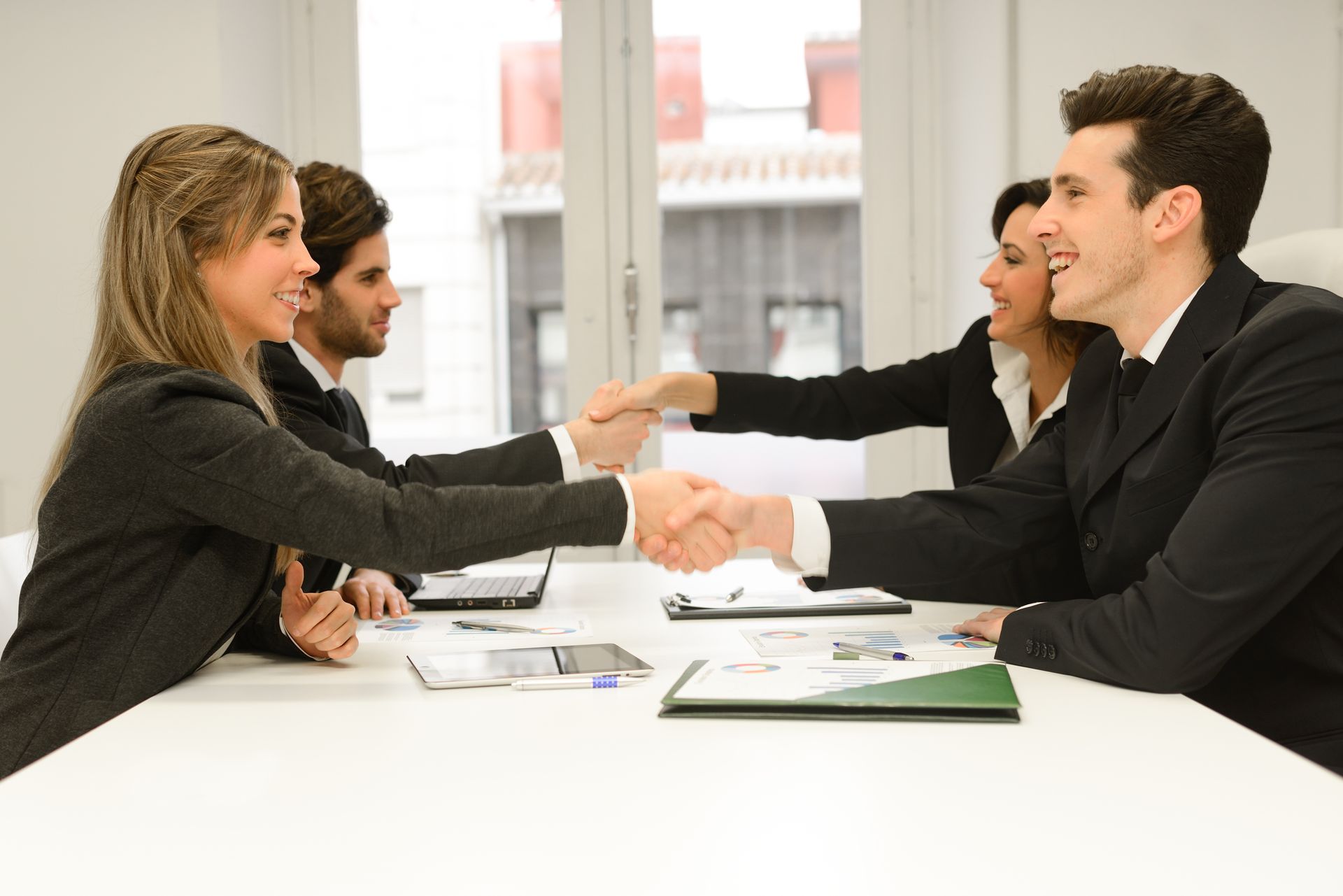 A group of business people are shaking hands at a table.