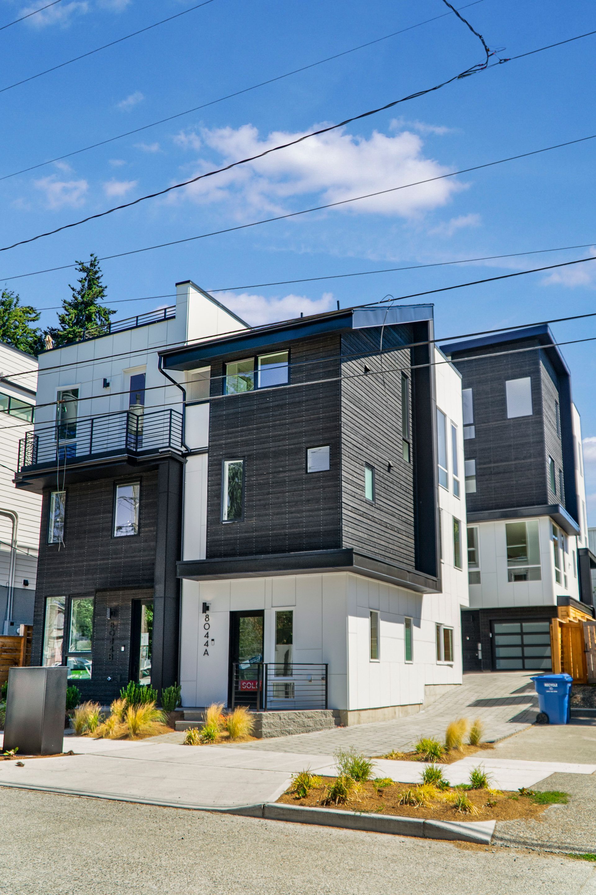A modern house with a lot of windows is sitting on the side of the road.