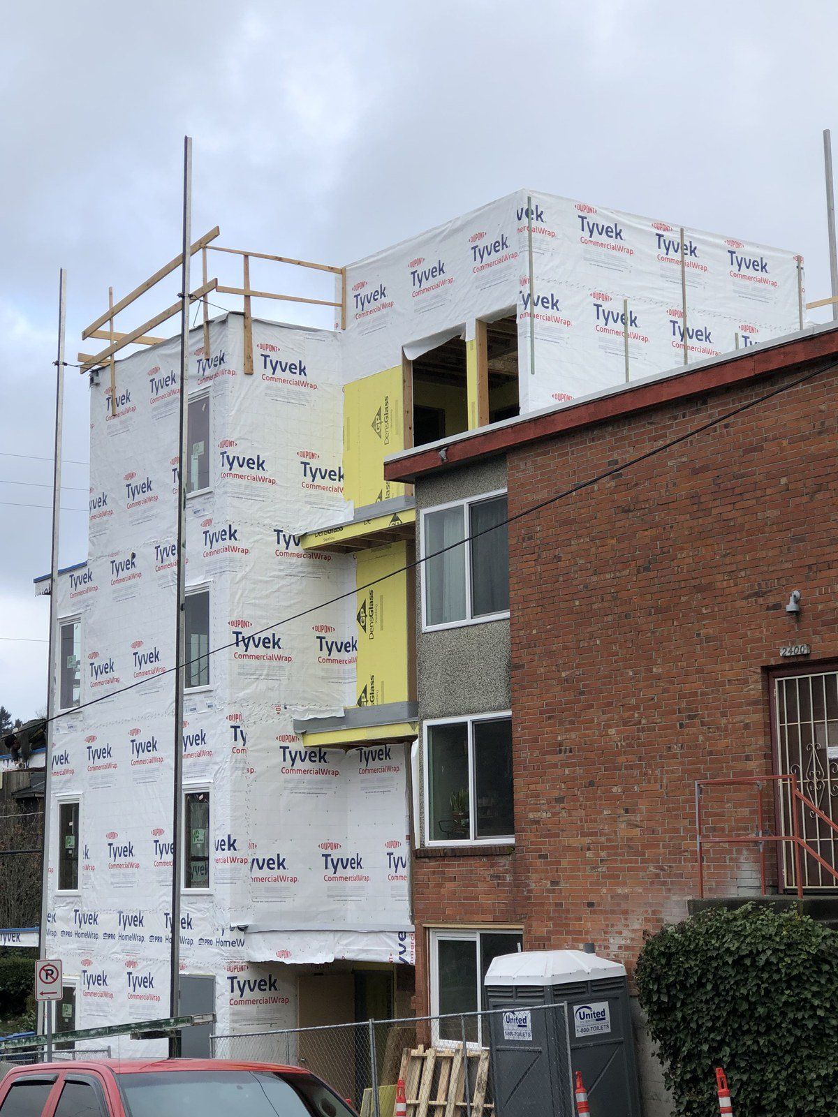 A building is being built next to a brick building.