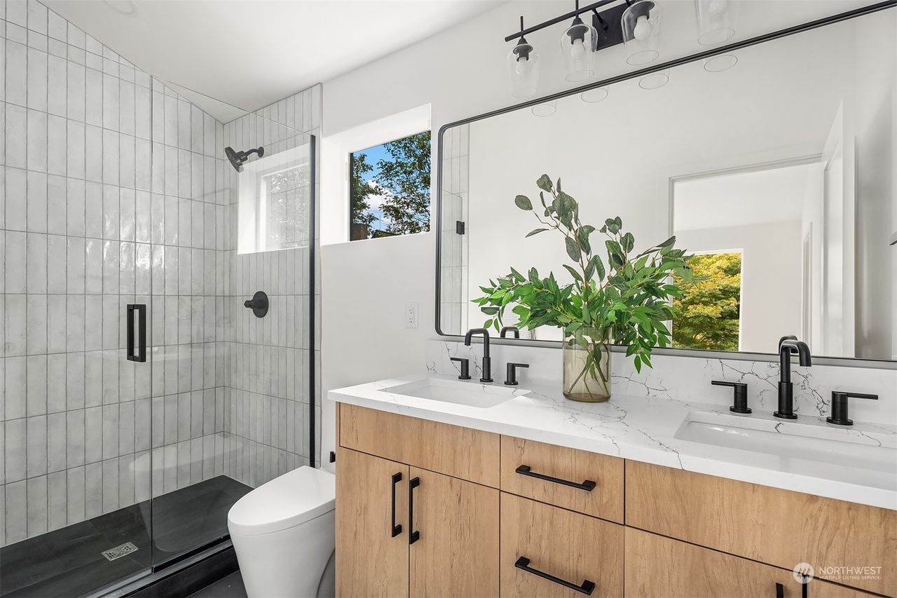 Modern bathroom with glass shower, double vanity, and plants by the sink