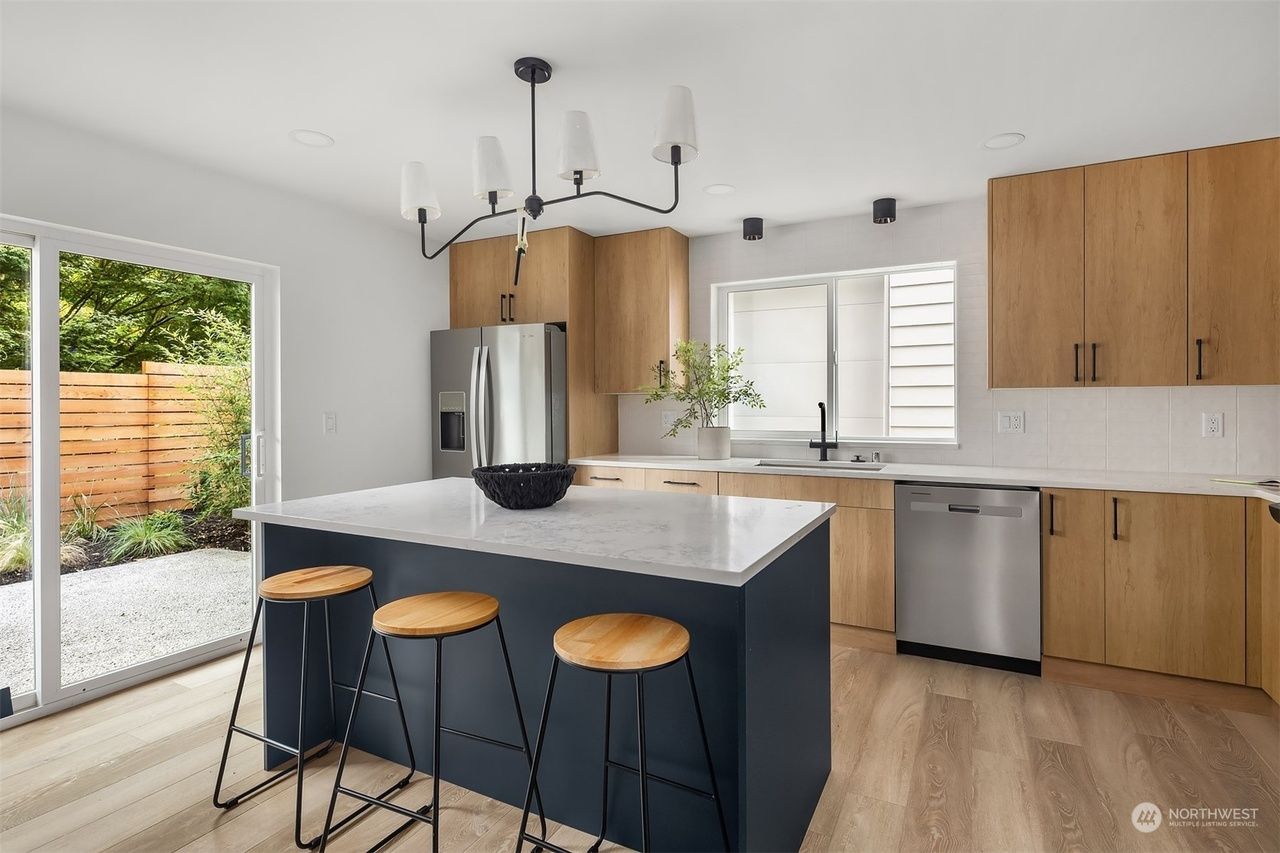Modern kitchen with navy island, wood cabinets, stainless appliances, and sliding glass door to patio