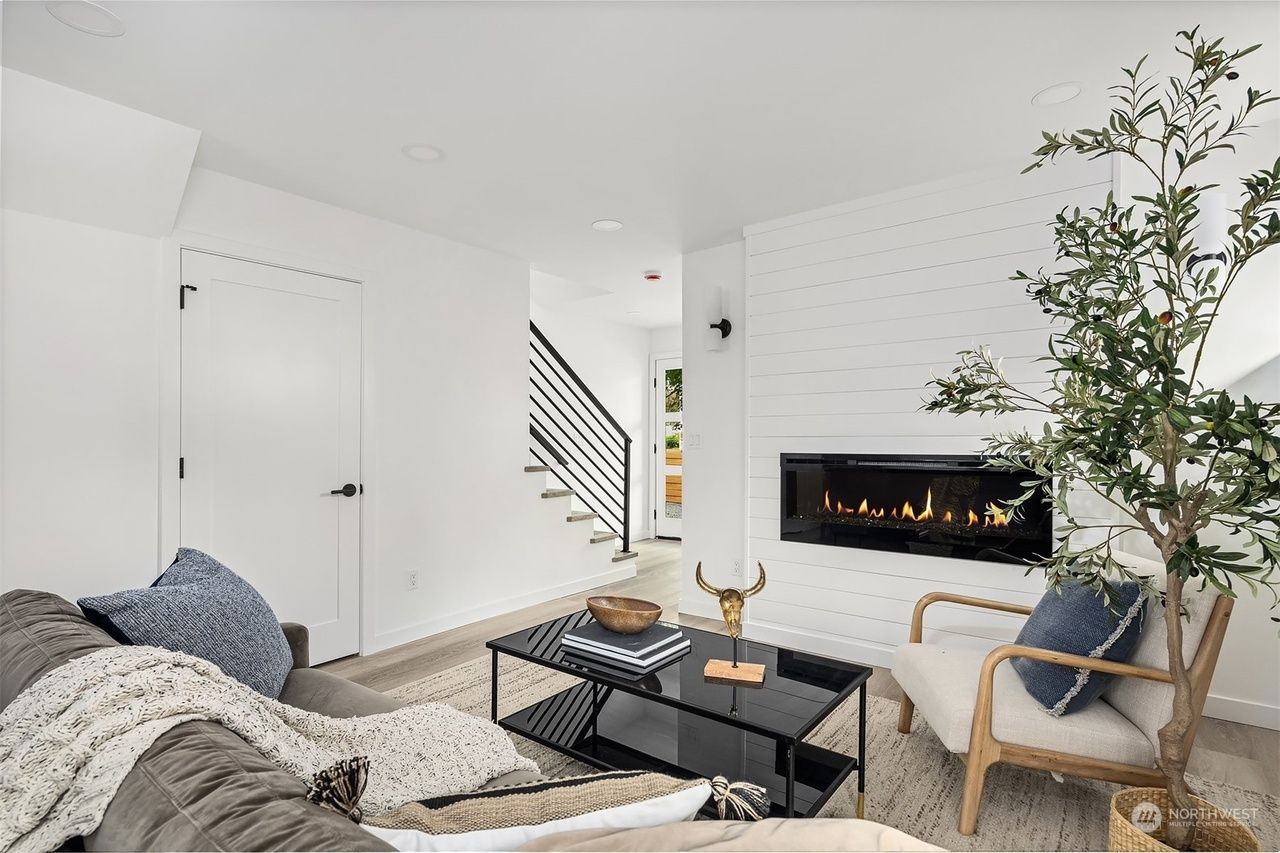 Bright modern living room with white walls, black fireplace, and gray sectional sofa