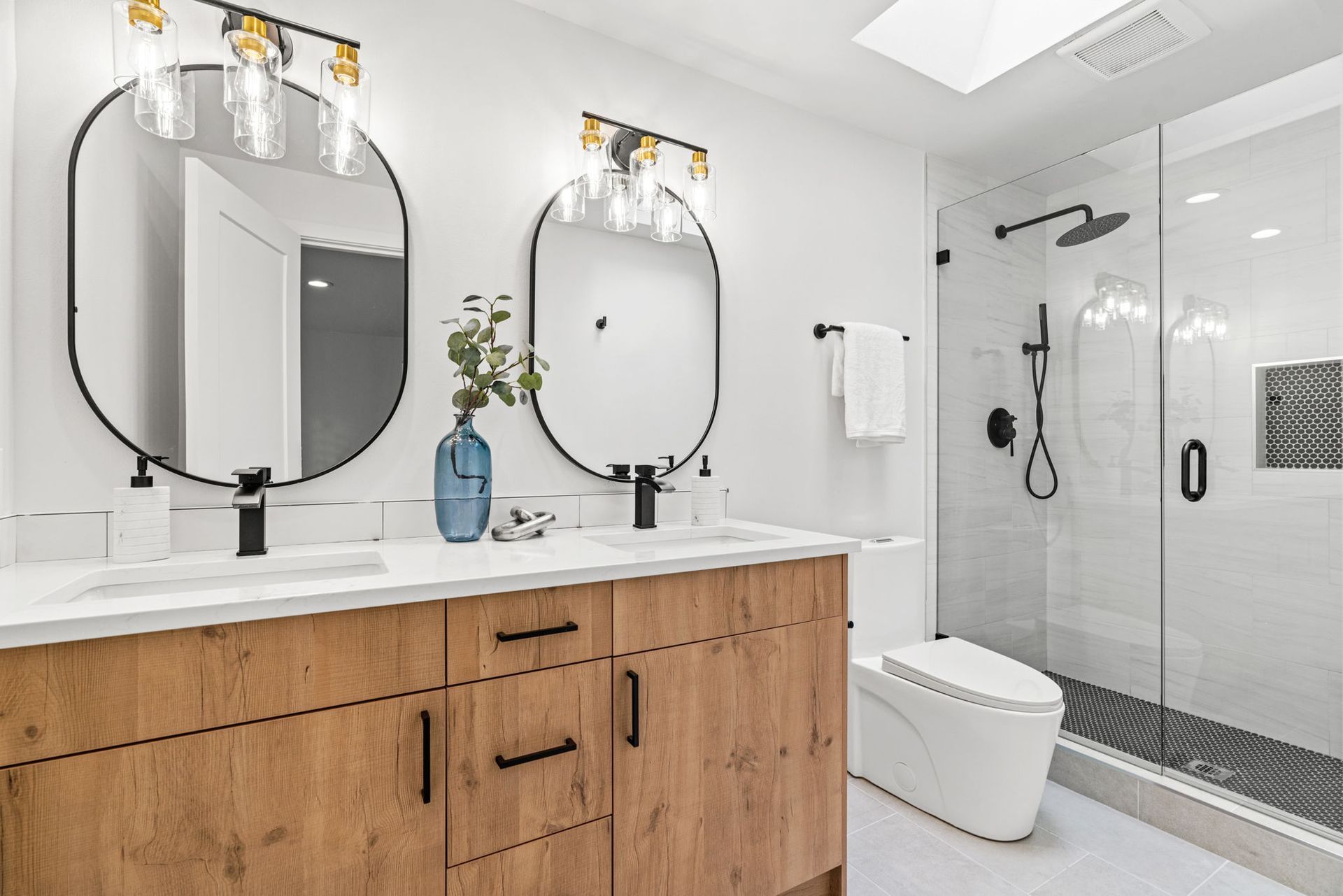 Modern bathroom with double vanity, round mirrors, and glass shower enclosure
