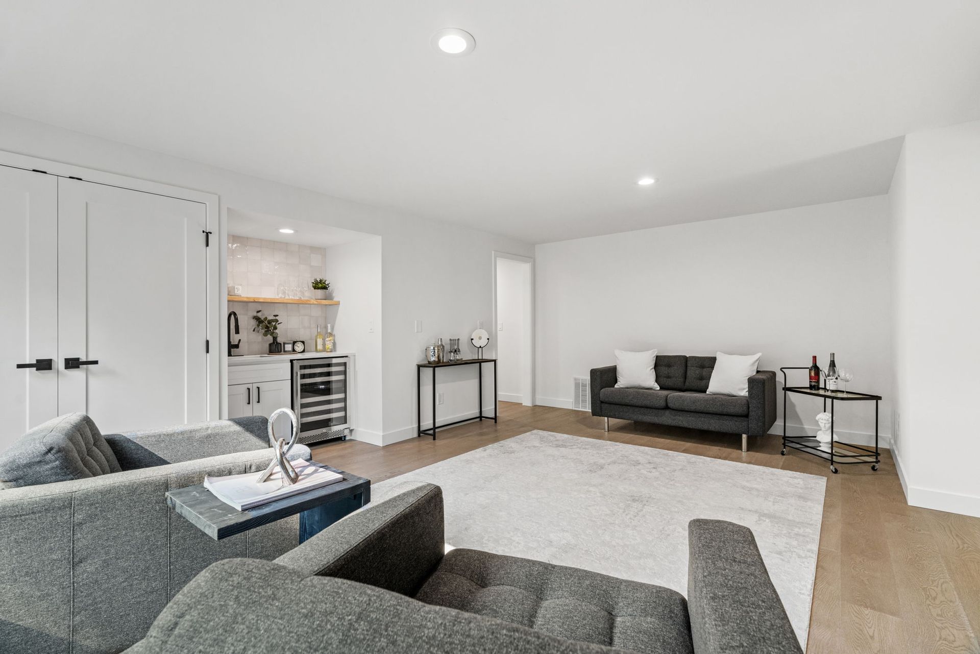 Bright modern living room with gray sofas, a white rug, wood floors, and a built-in desk nook.