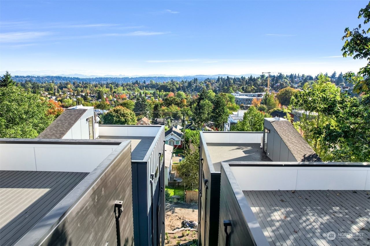 Modern buildings overlooking a tree-lined neighborhood under a bright blue sky