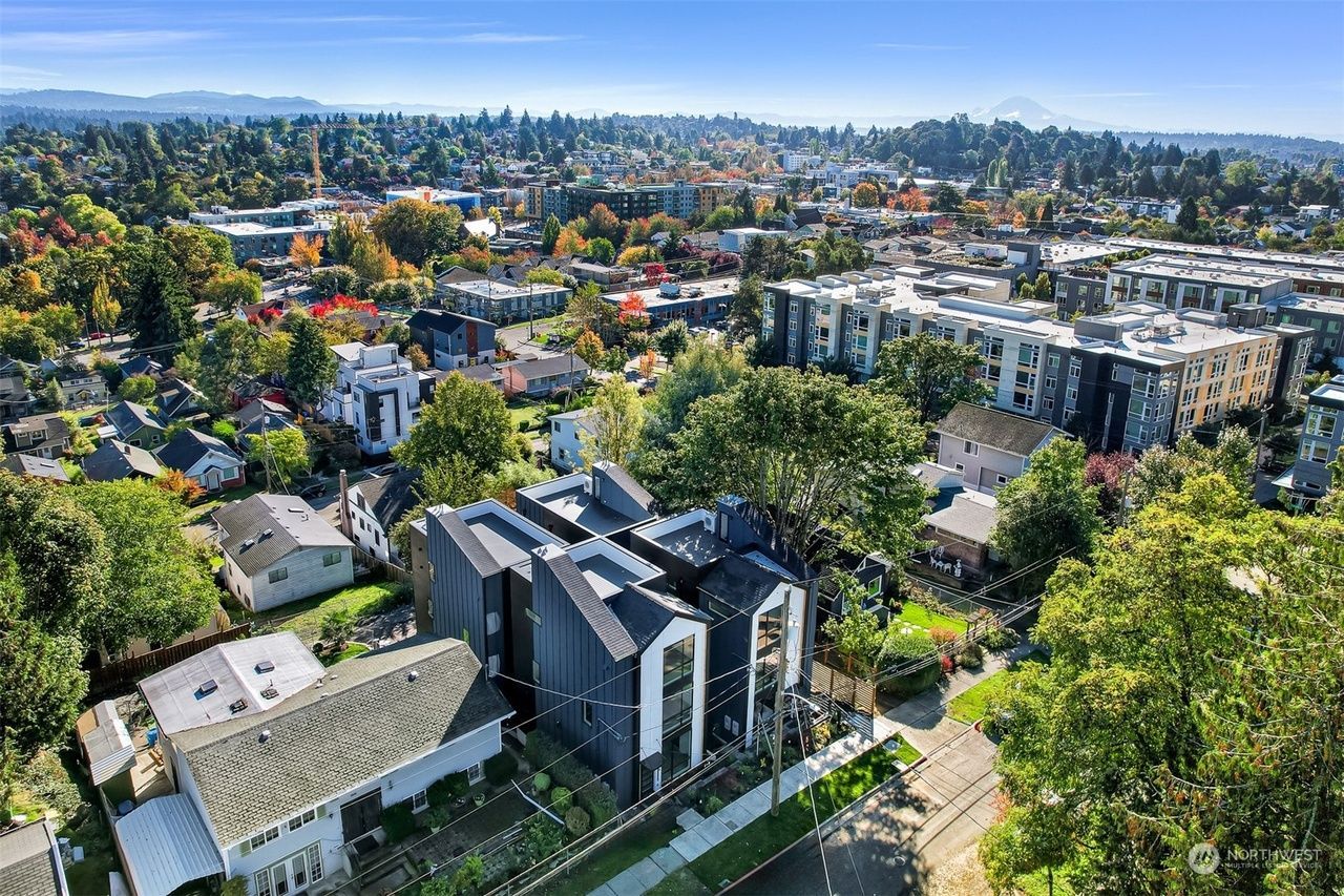 Aerial view of a suburban neighborhood with tree-lined streets and modern buildings under a clear sky
