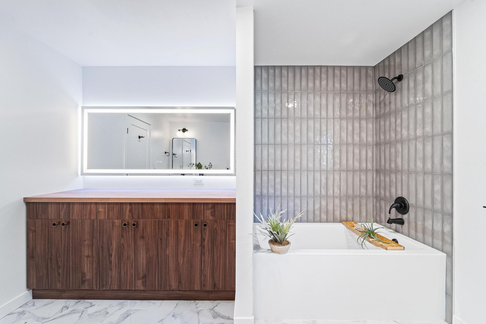 Modern bathroom with wood vanity, backlit mirror, and tiled tub shower with a black fixture