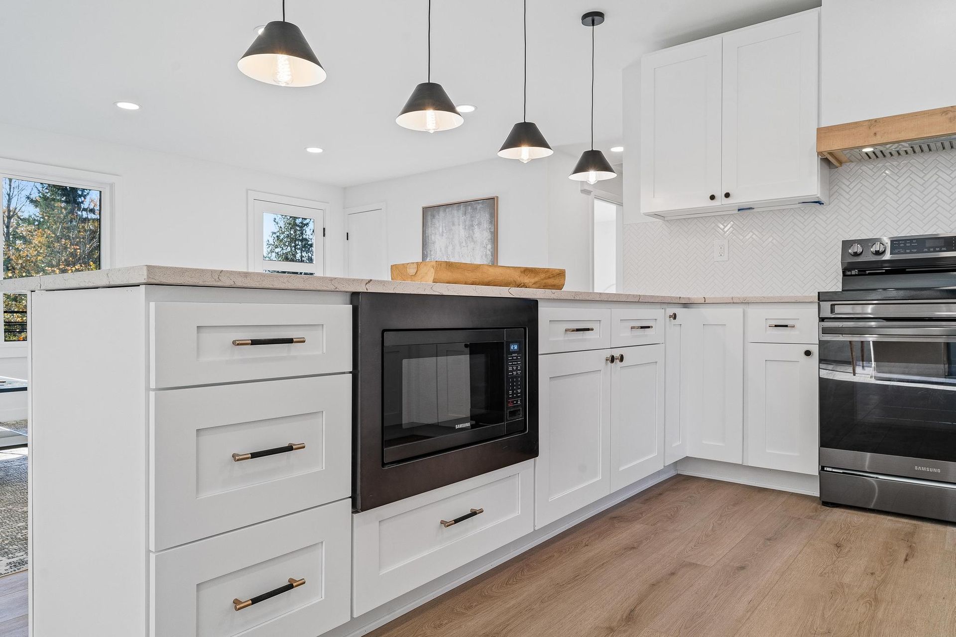 Bright white kitchen with island, pendant lights, wood countertops, and black appliances