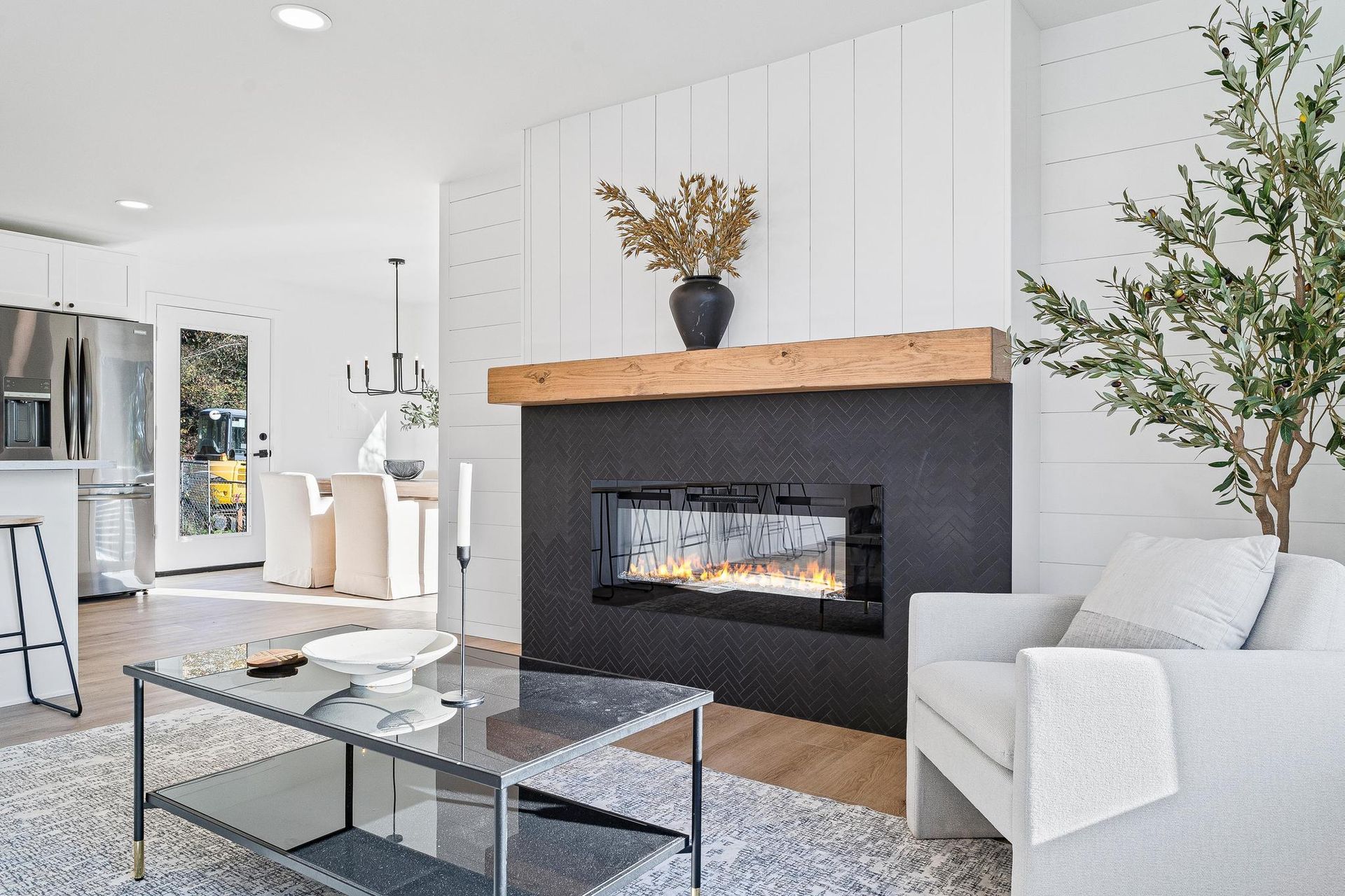 Bright living room with modern fireplace, white walls, glass coffee table, and light armchairs