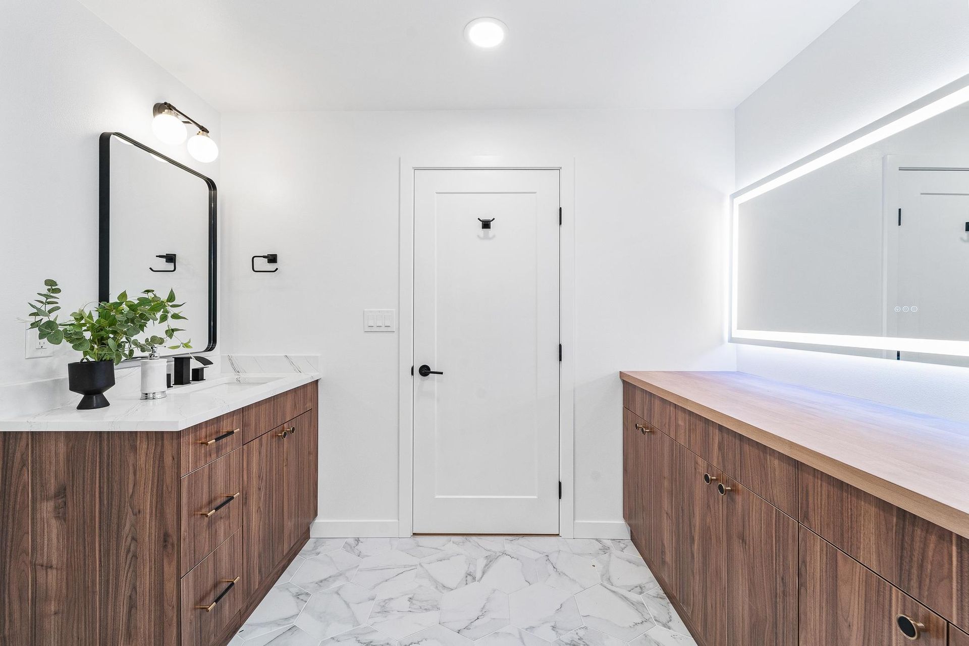 Bright modern bathroom with double wood vanities, white walls, and marble flooring