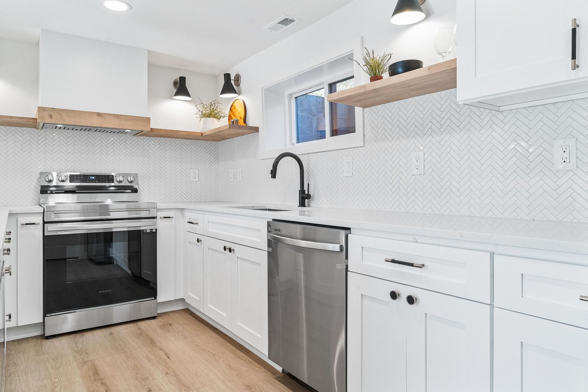 Bright white modern kitchen with stainless steel appliances, open shelves, and wood floors