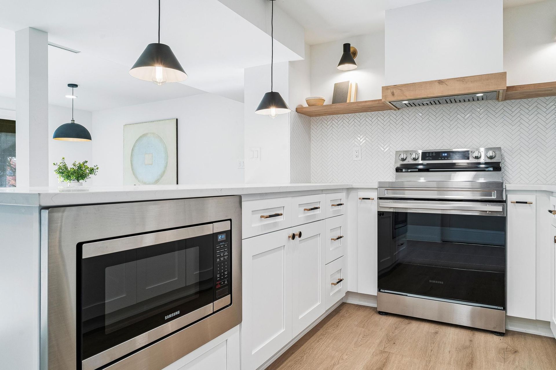 Bright modern kitchen with white cabinets, stainless steel appliances, and pendant lights