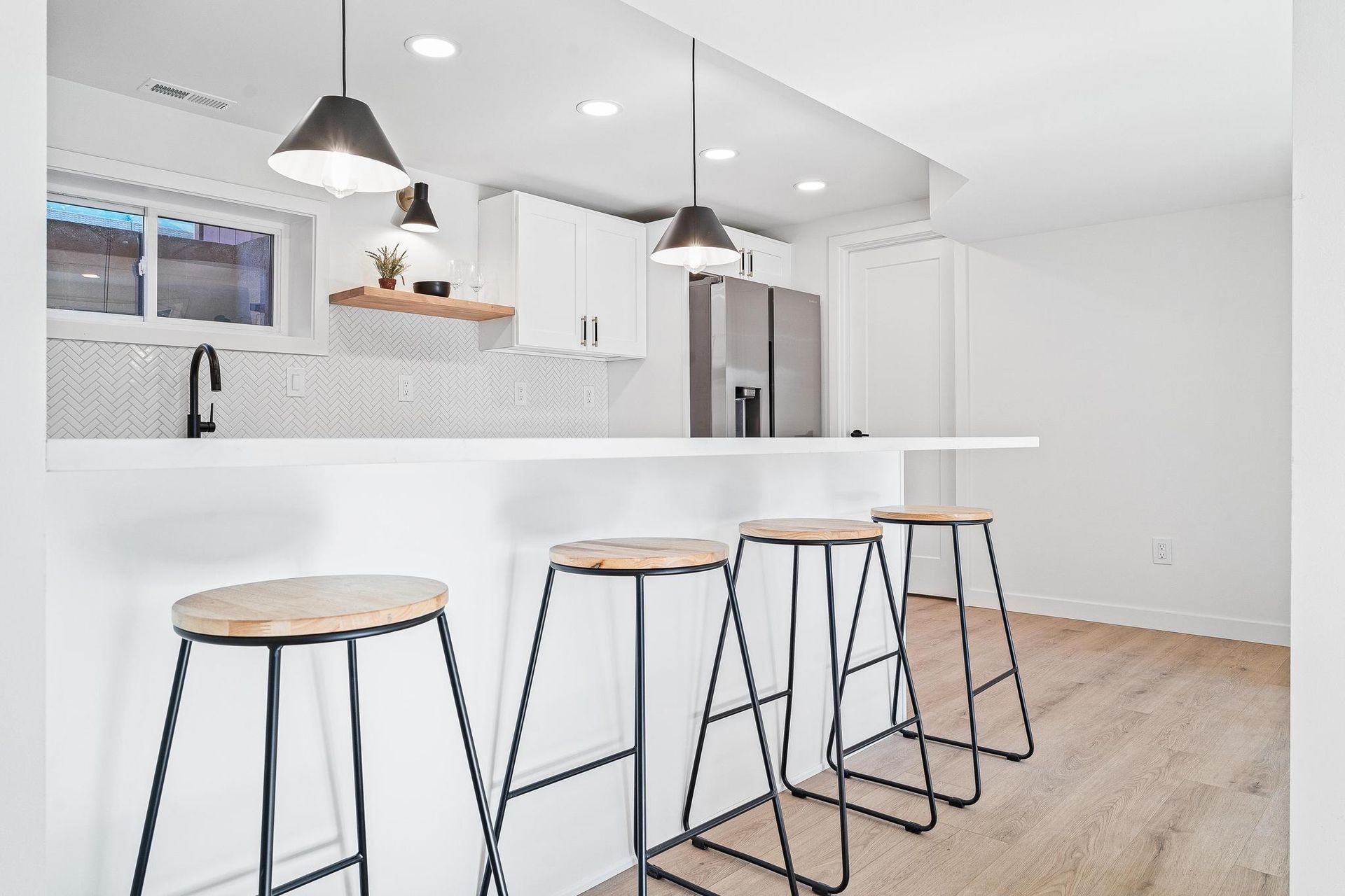 Bright modern kitchen with white cabinets, island stools, and pendant lights