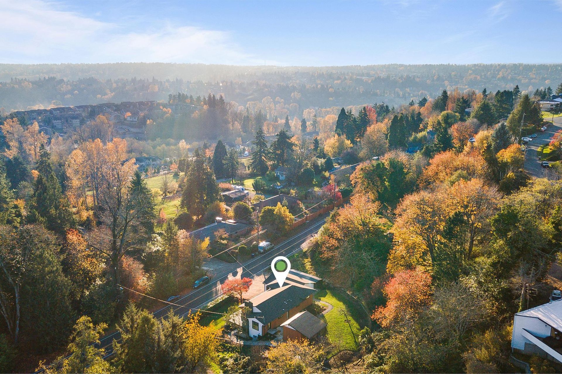 Autumn aerial view of a wooded neighborhood with colorful trees and houses in soft morning light