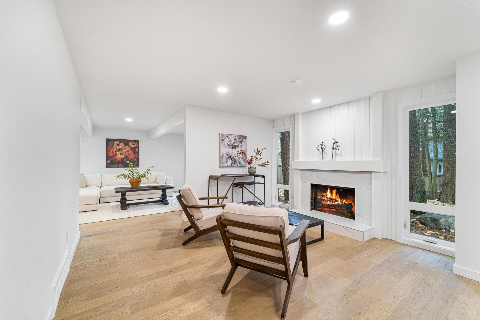 Bright modern living room with white walls, wood floors, fireplace, and minimalist furniture