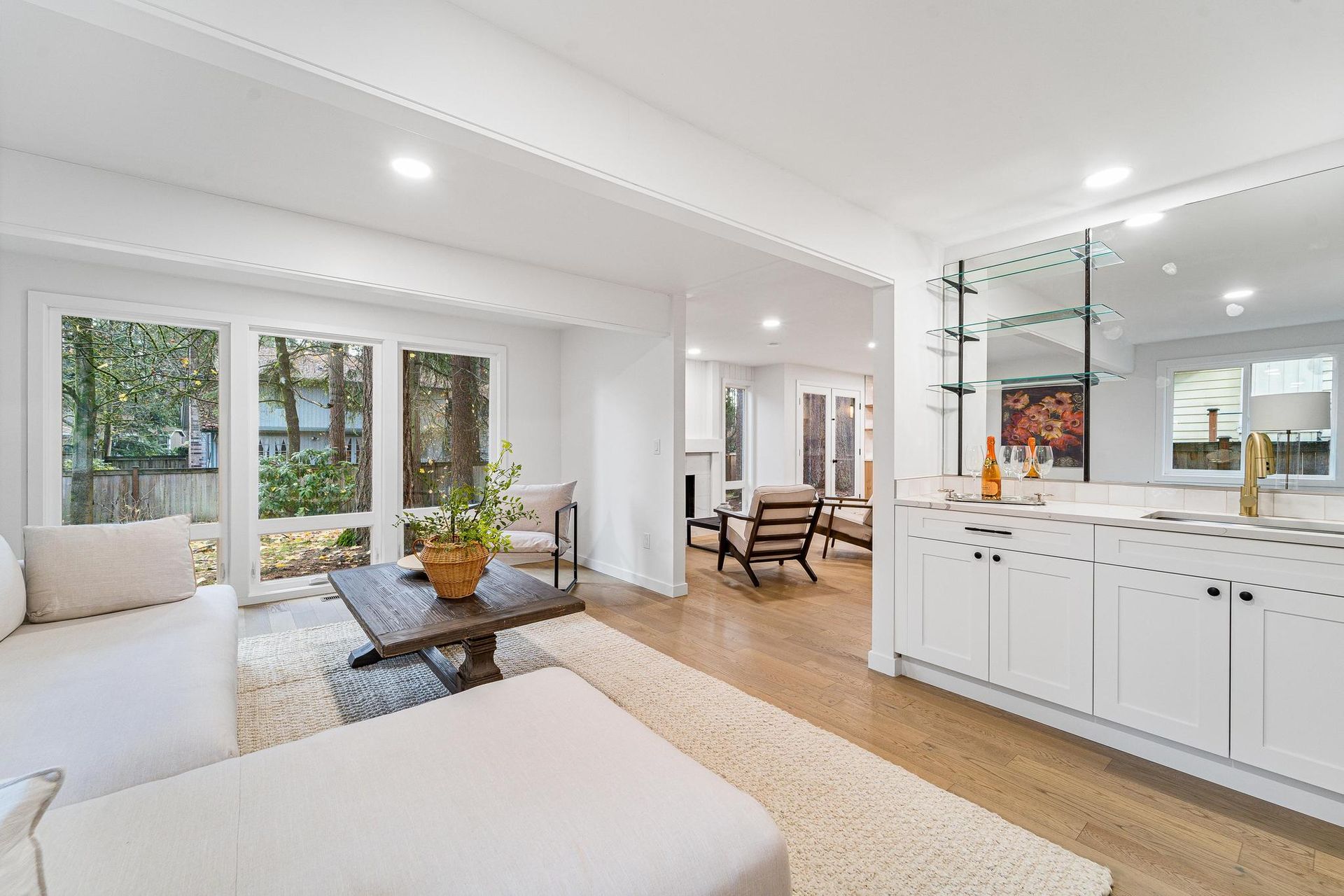 Bright modern living room with white sofa, coffee table, and open kitchen with marble island.