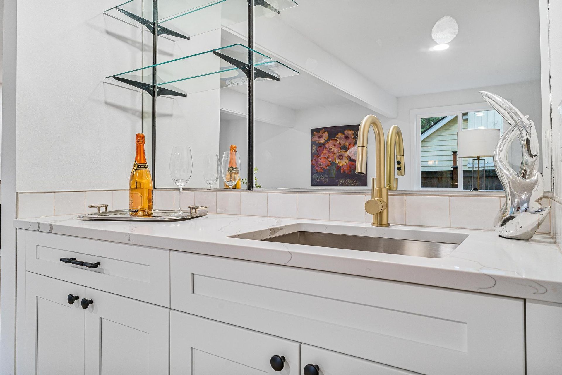 Bright modern bathroom with double sink, white vanity, mirrors, and glass shelves
