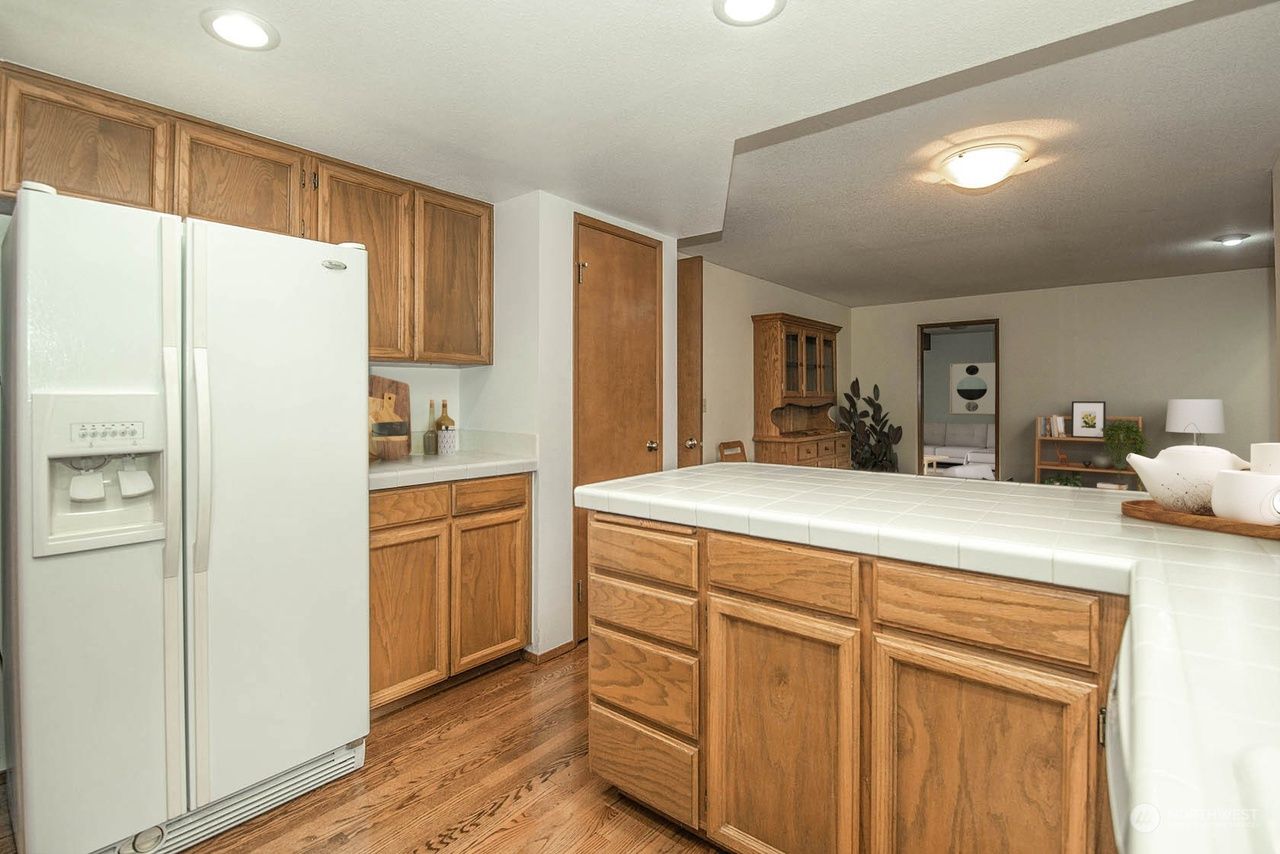 Bright kitchen with white refrigerator, wood cabinets, and a large island counter
