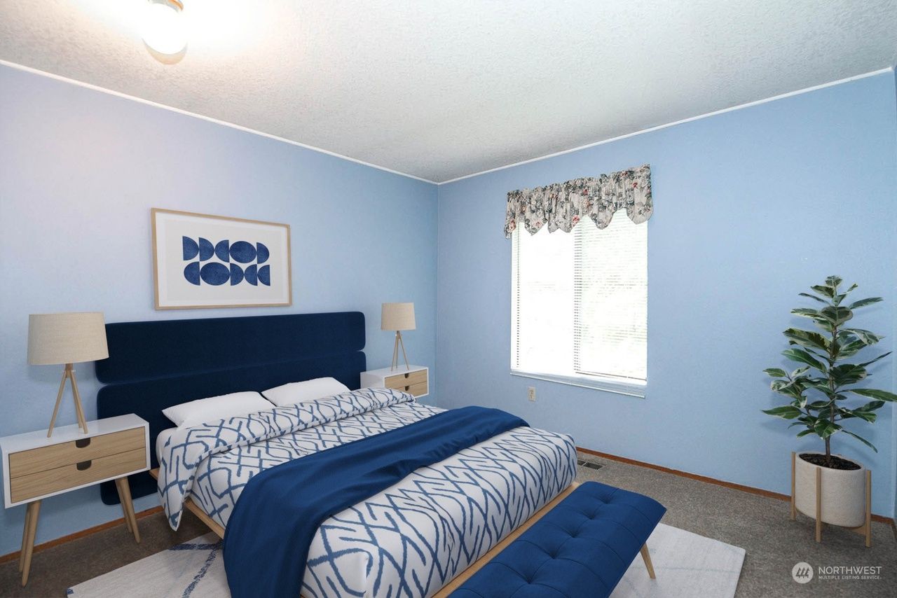 Blue bedroom with navy bed, white walls, bedside lamps, window, and a potted plant