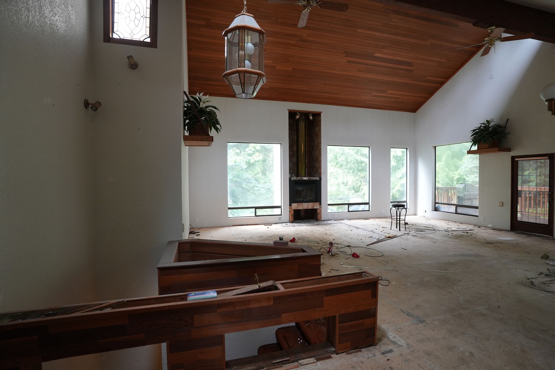 Abandoned church interior with pews, debris, and large windows under a wooden ceiling