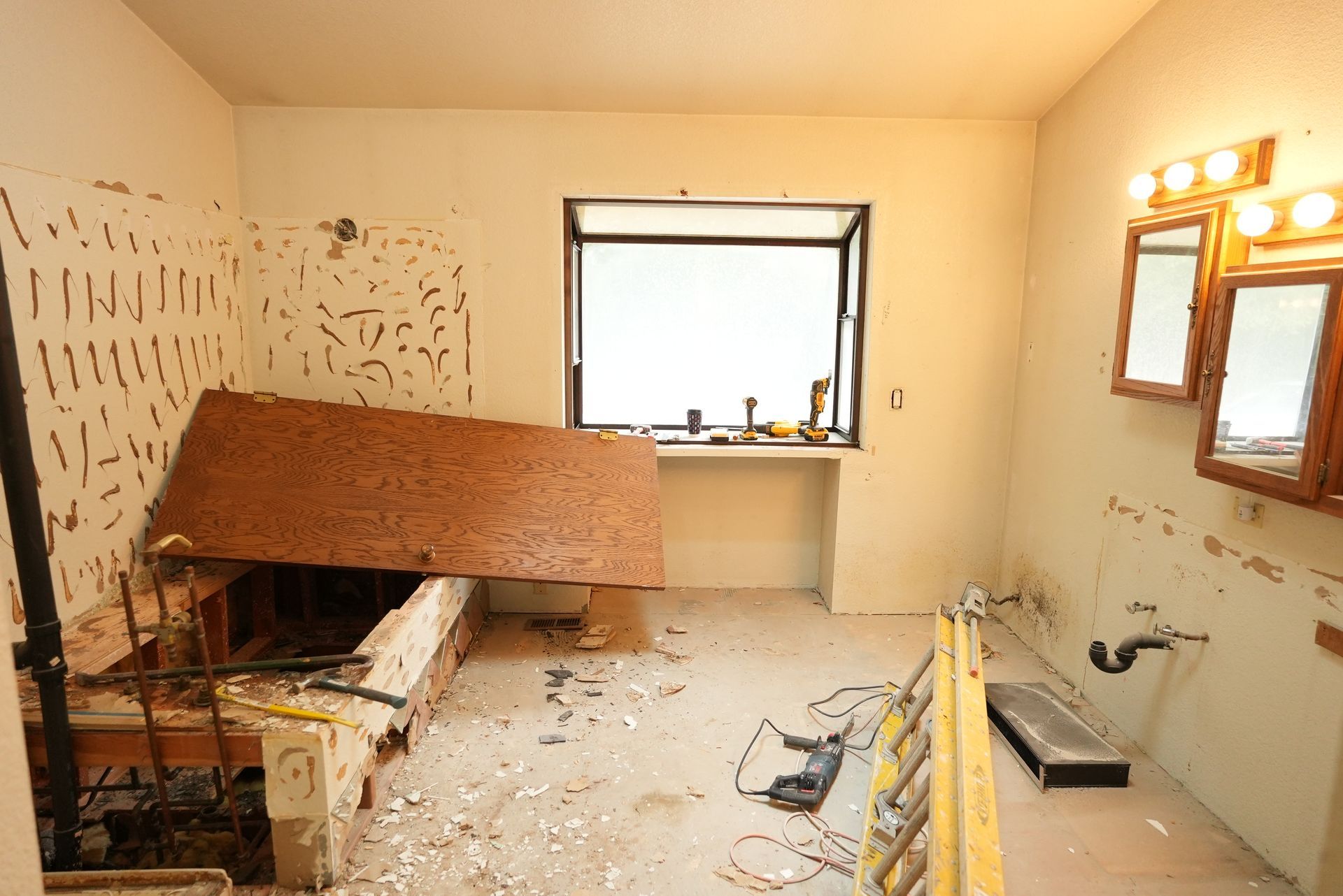 Damaged bathroom with debris, collapsed cabinet, and broken fixtures under renovation