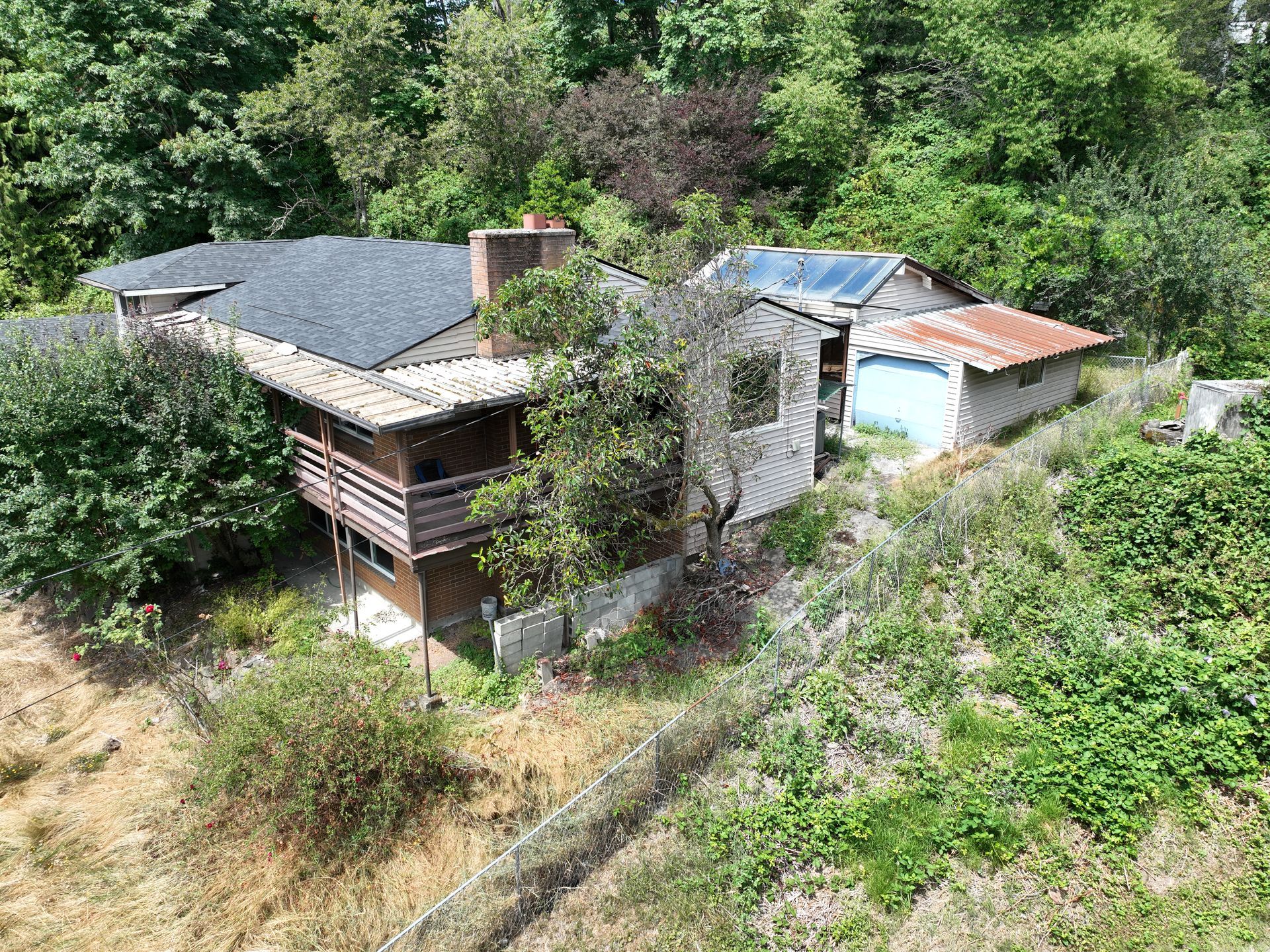 Two small rustic houses with gray roofs nestled on a wooded hillside