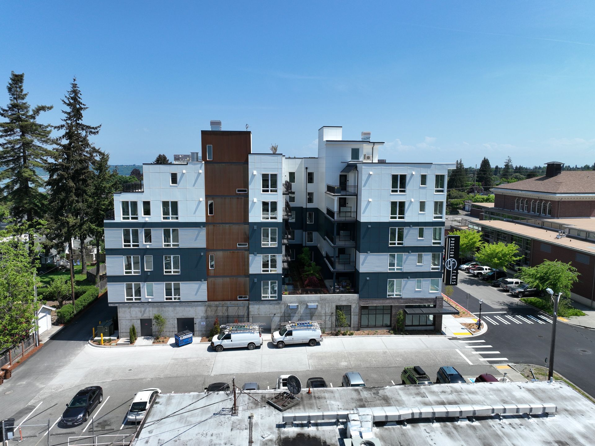 An aerial view of a large apartment building with cars parked in front of it.