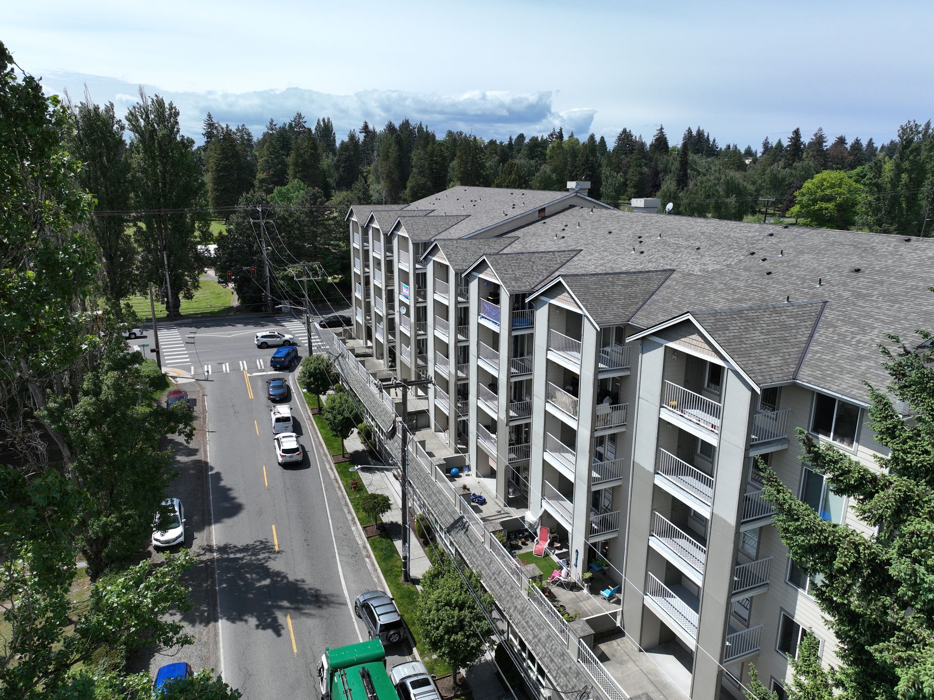 An aerial view of a large apartment building surrounded by trees and a street.