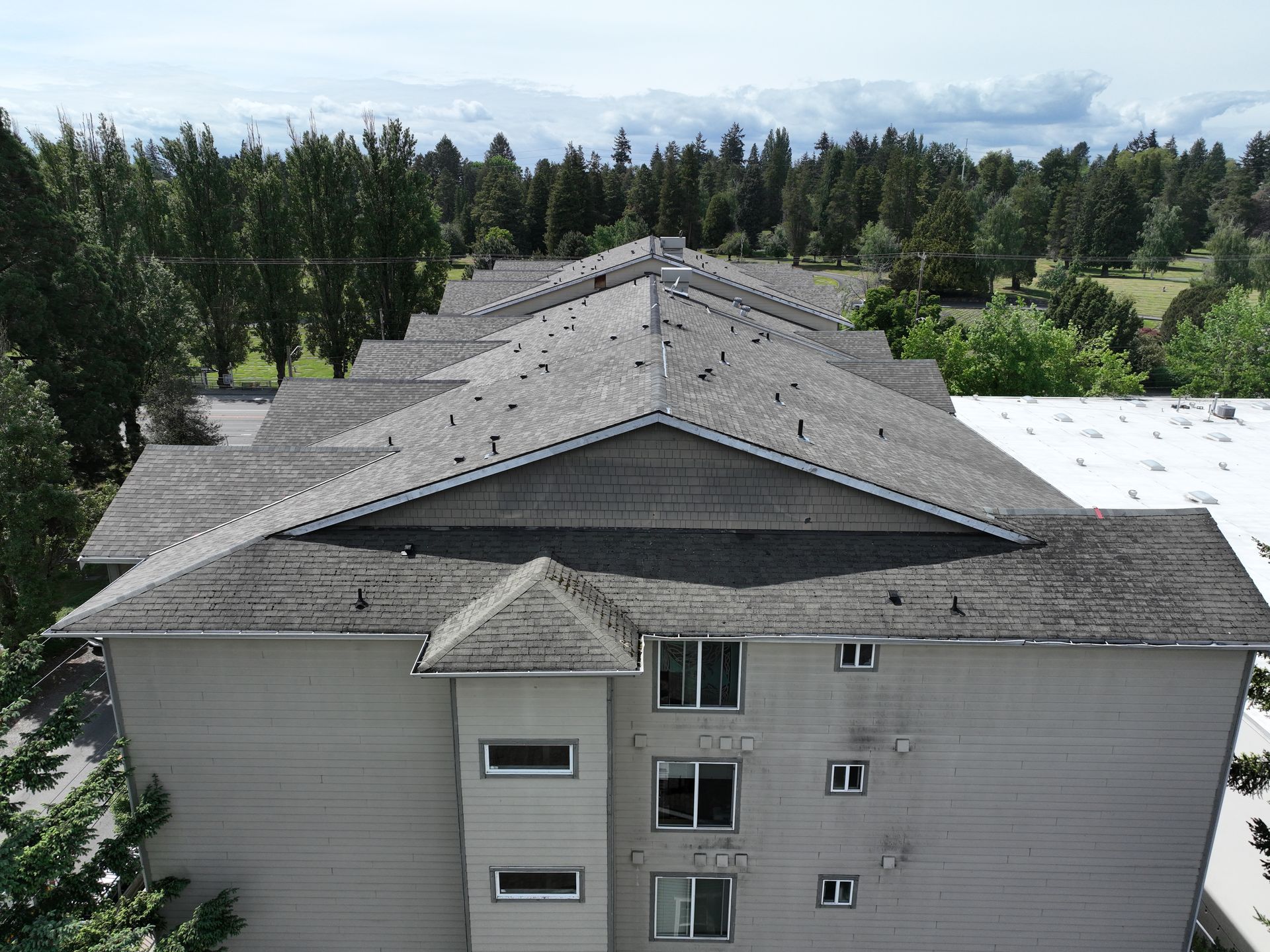 An aerial view of a large apartment building with trees in the background.