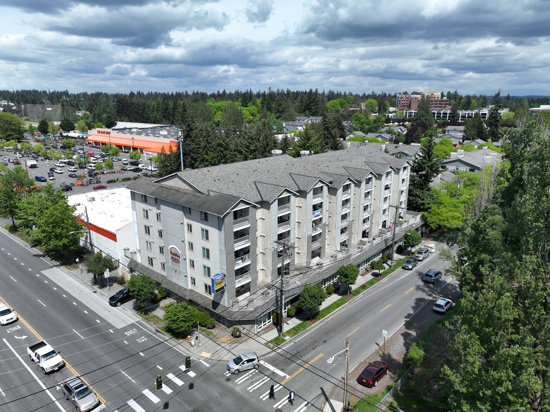 An aerial view of a large apartment building on the corner of a city street.
