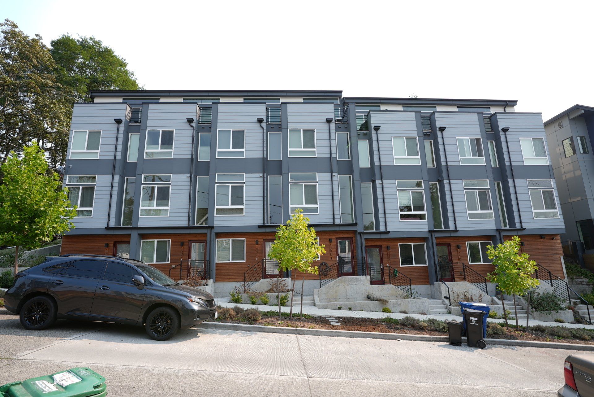 A car is parked in front of a row of apartment buildings