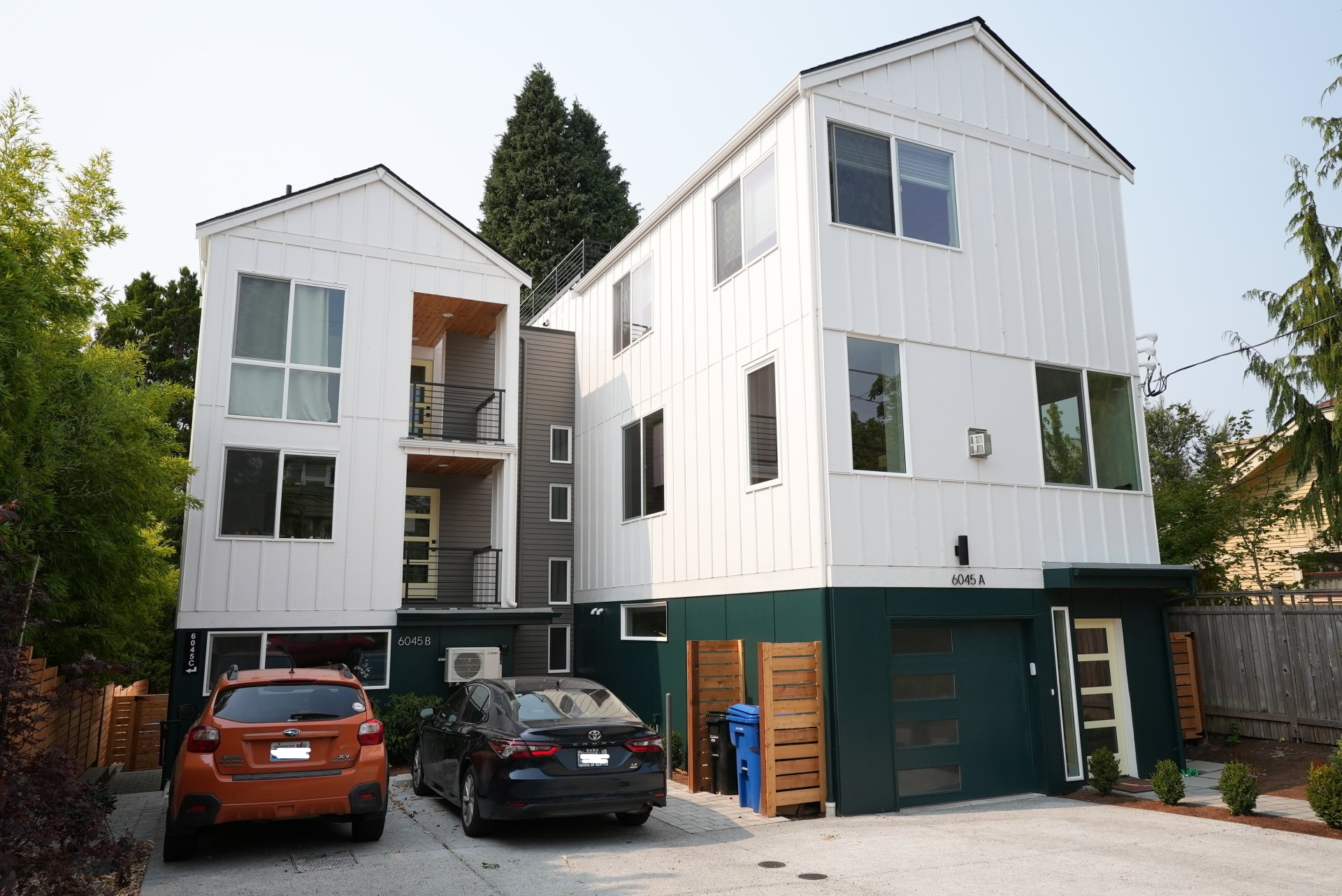 Two cars are parked in front of a large white building