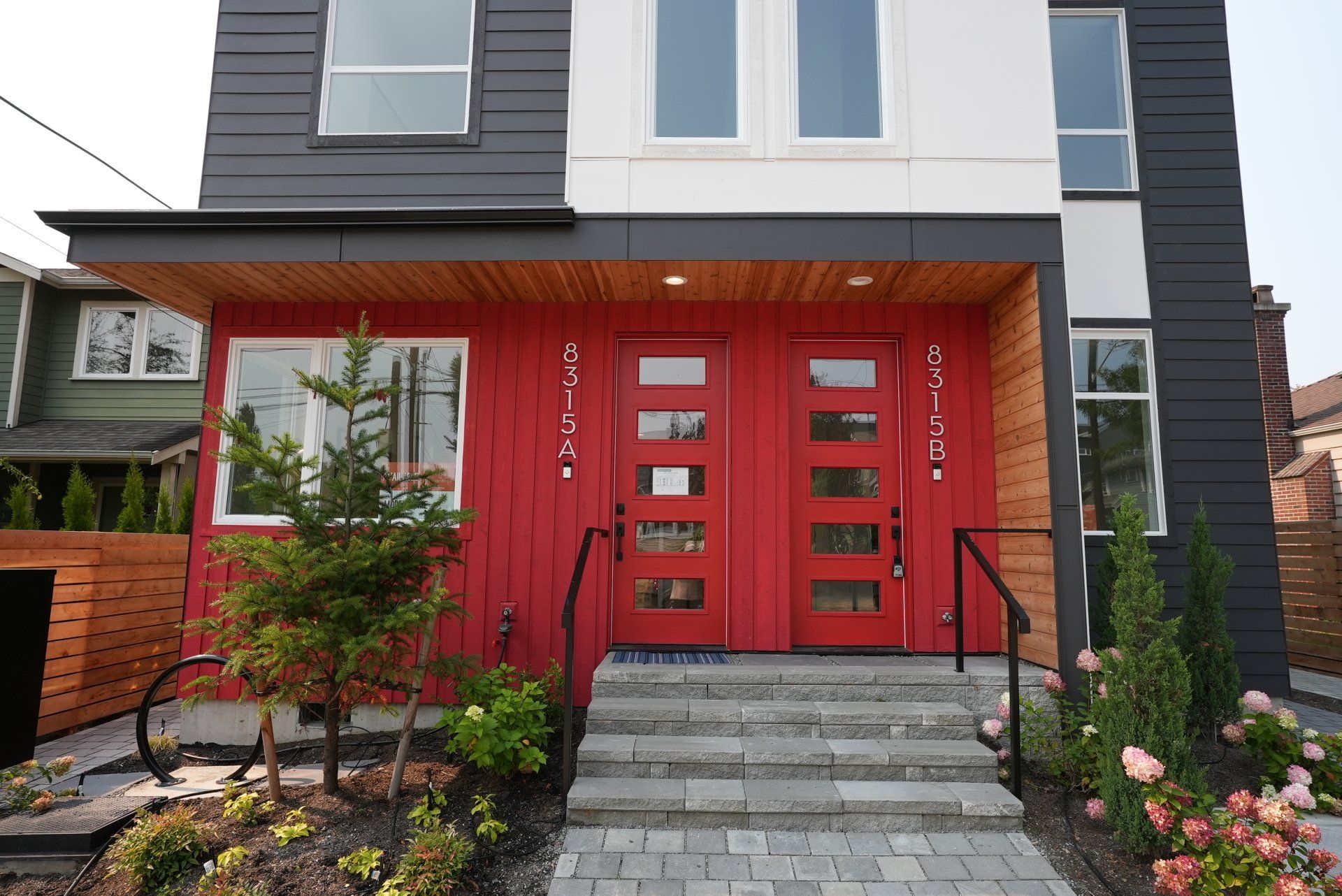 A black and white house with red doors and stairs
