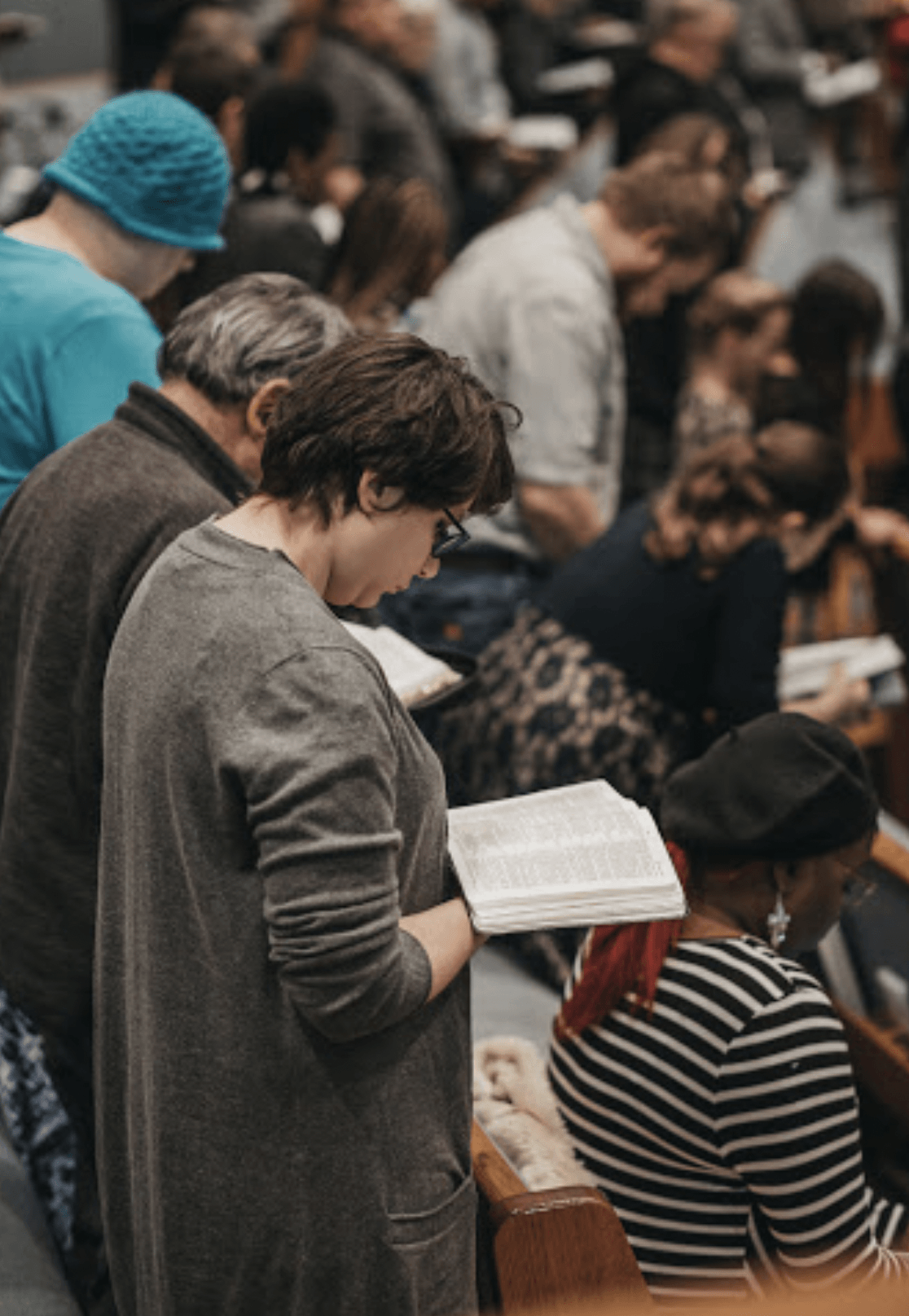 A woman is reading a book in front of a crowd of people.