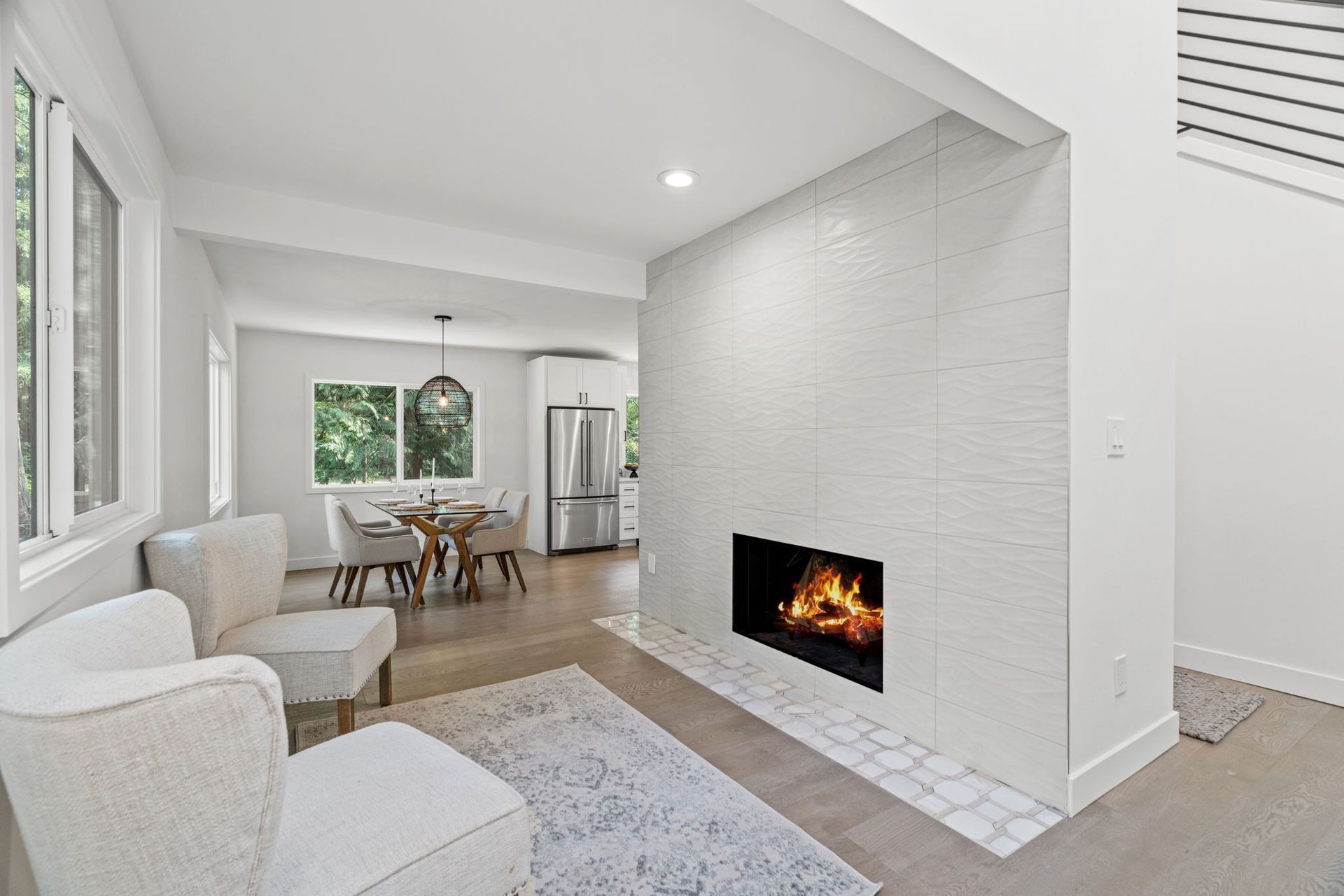 A living room with a fireplace and a dining room in the background.