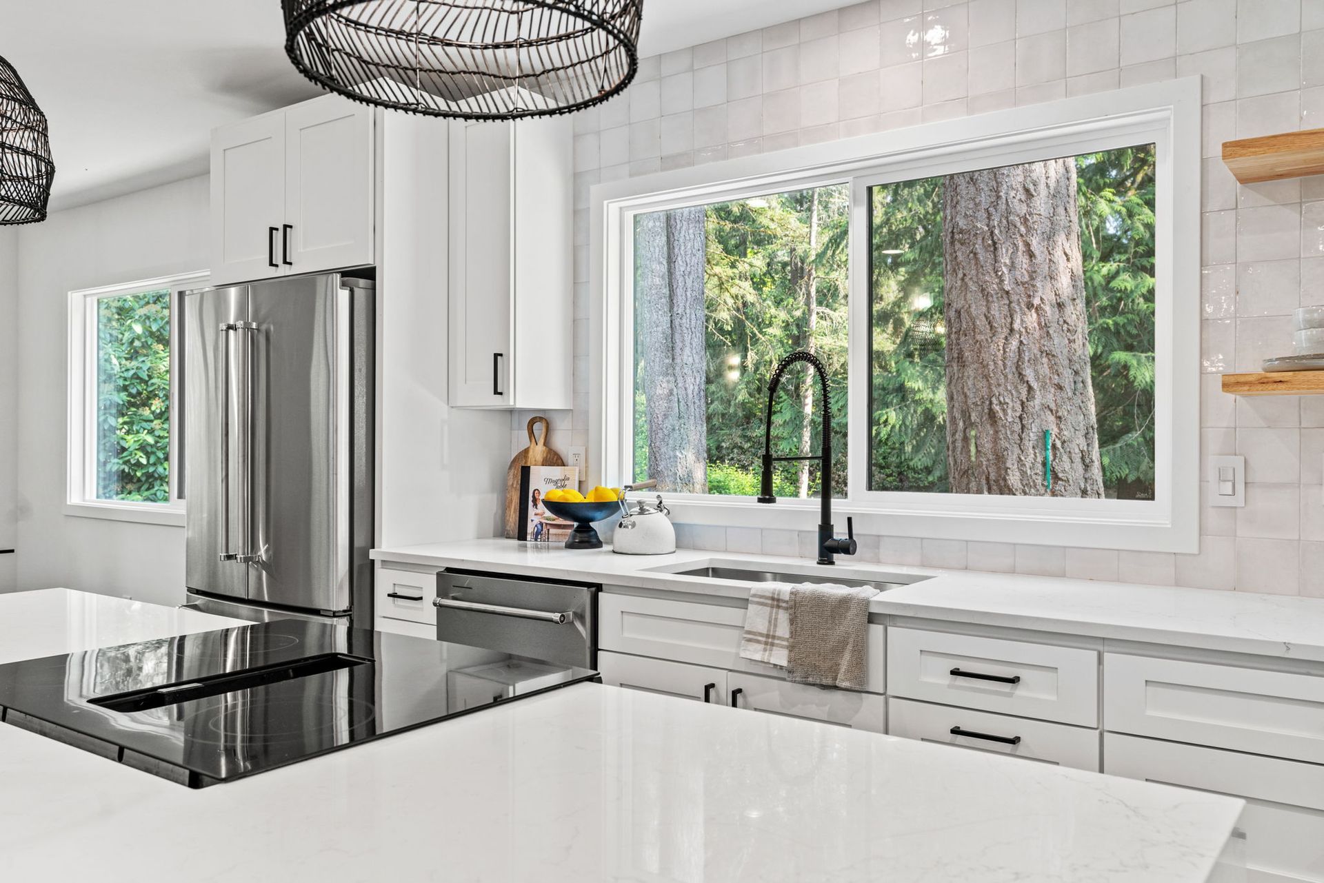 A kitchen with white cabinets , stainless steel appliances , a sink and a refrigerator.