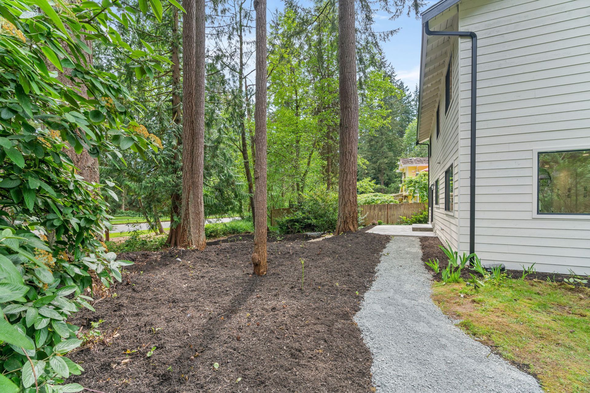 A path leading to a white house surrounded by trees.