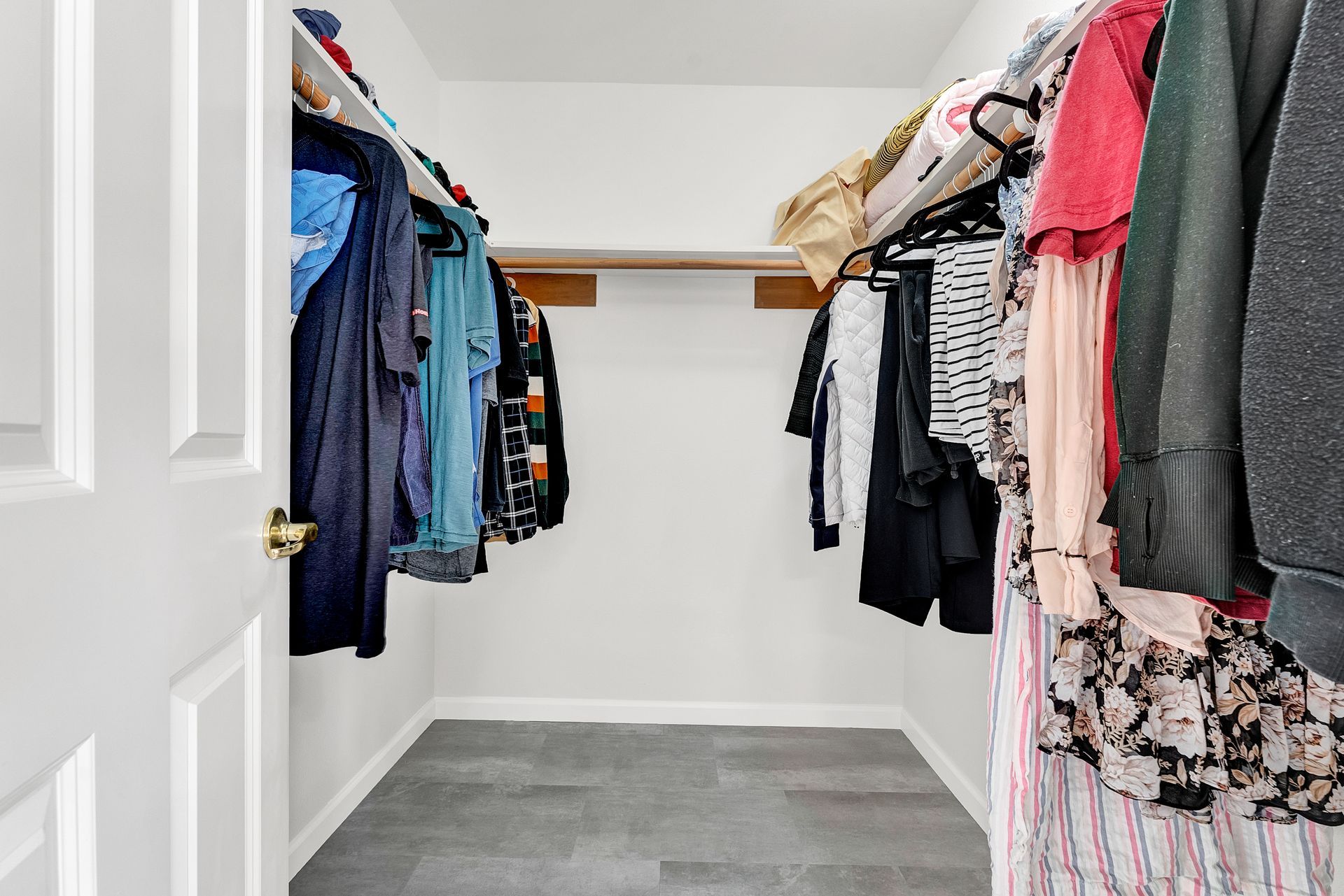 A walk in closet filled with lots of clothes.