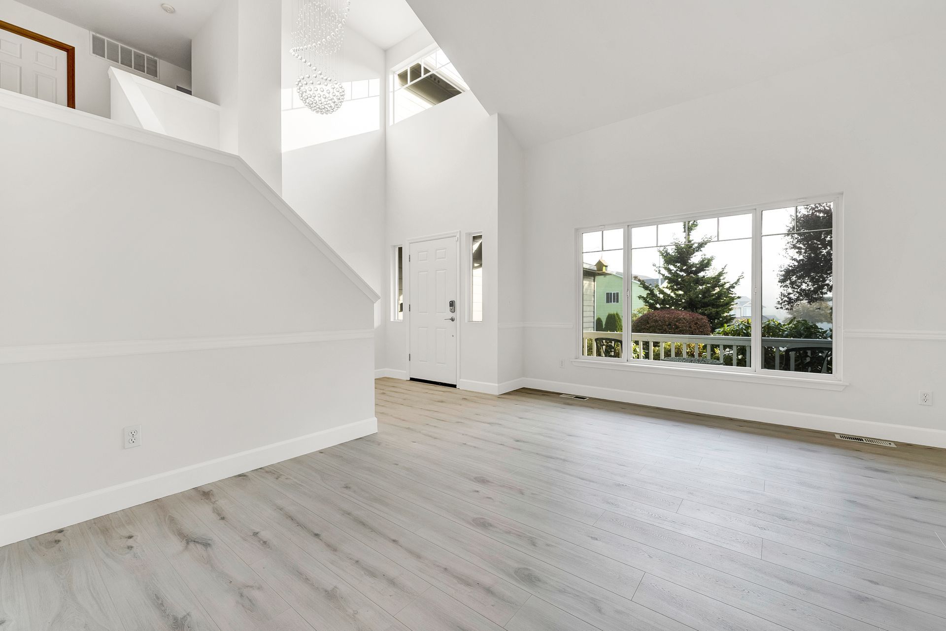 An empty living room with hardwood floors and white walls