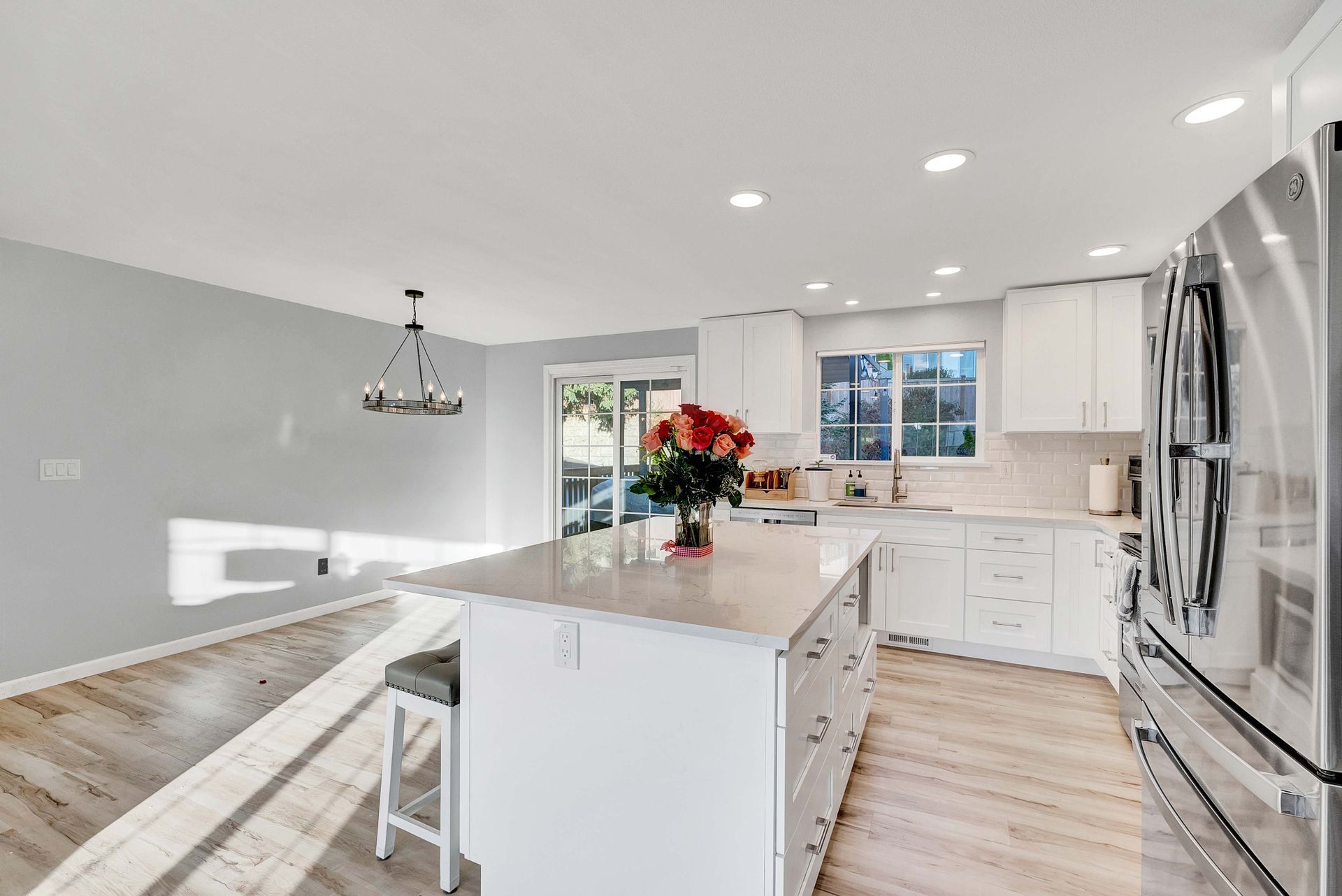 Bright modern white kitchen with island, stainless appliances, and hardwood floors