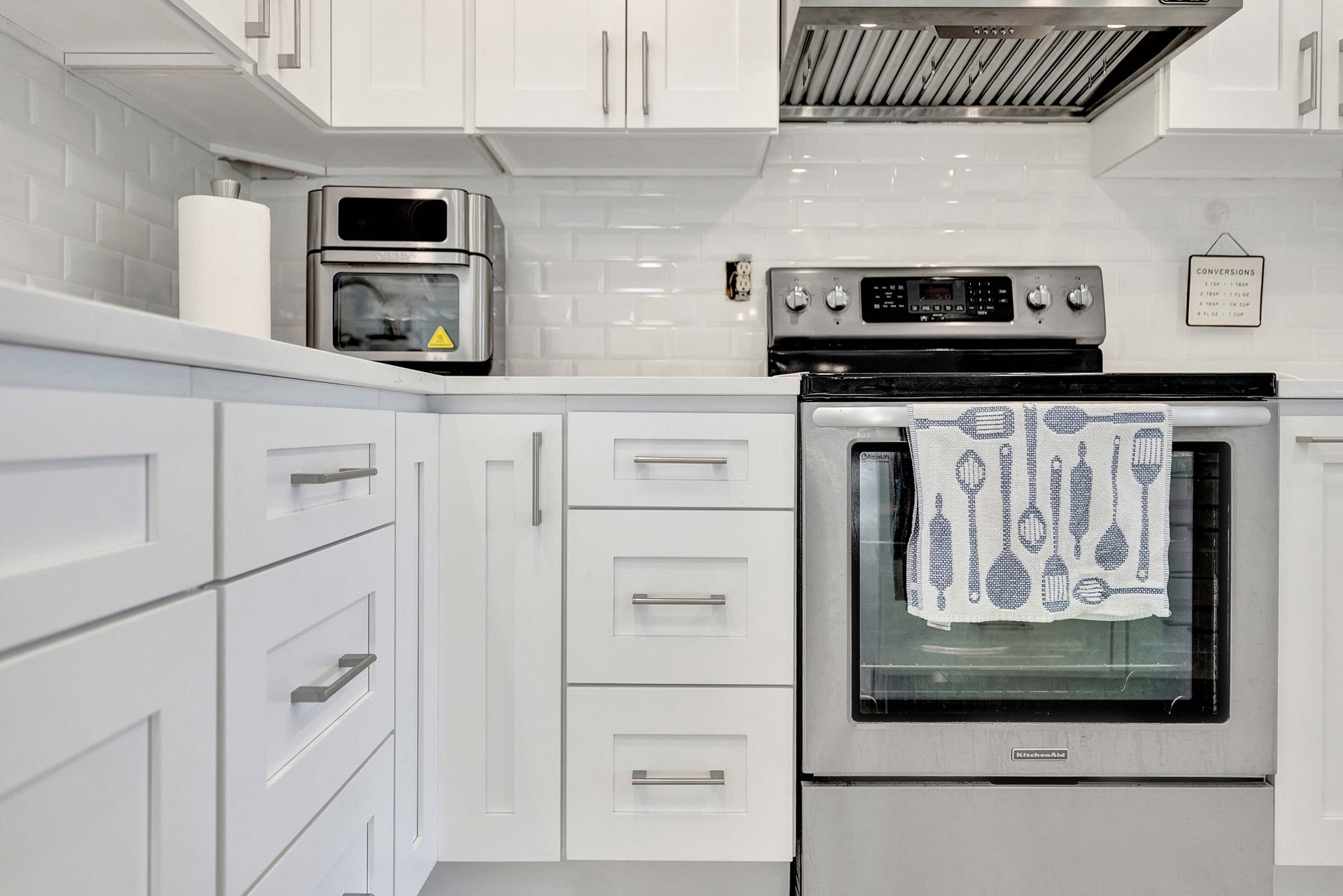 Bright white kitchen with stainless steel oven, cabinets, and countertop appliances
