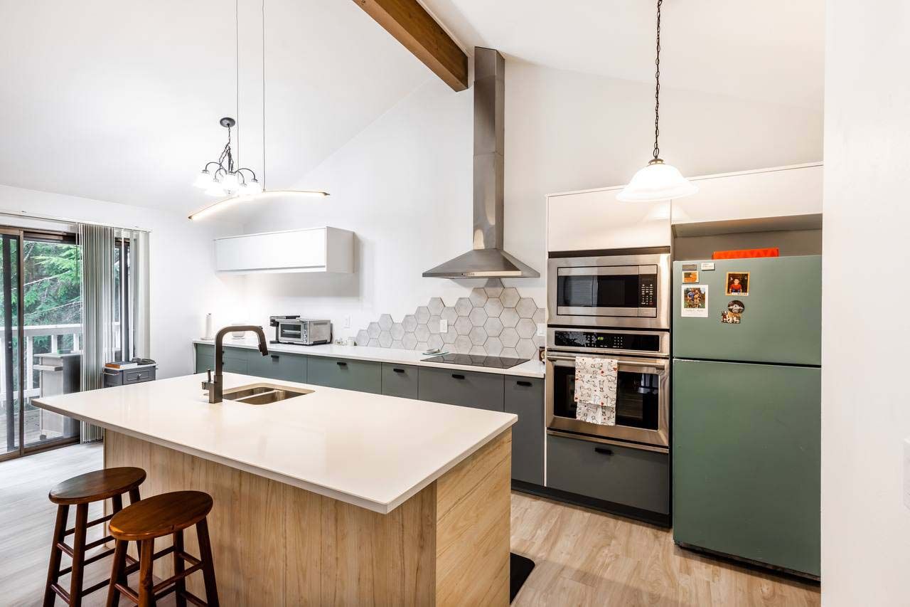 Modern kitchen with island, pendant lights, stainless appliances, and a green refrigerator