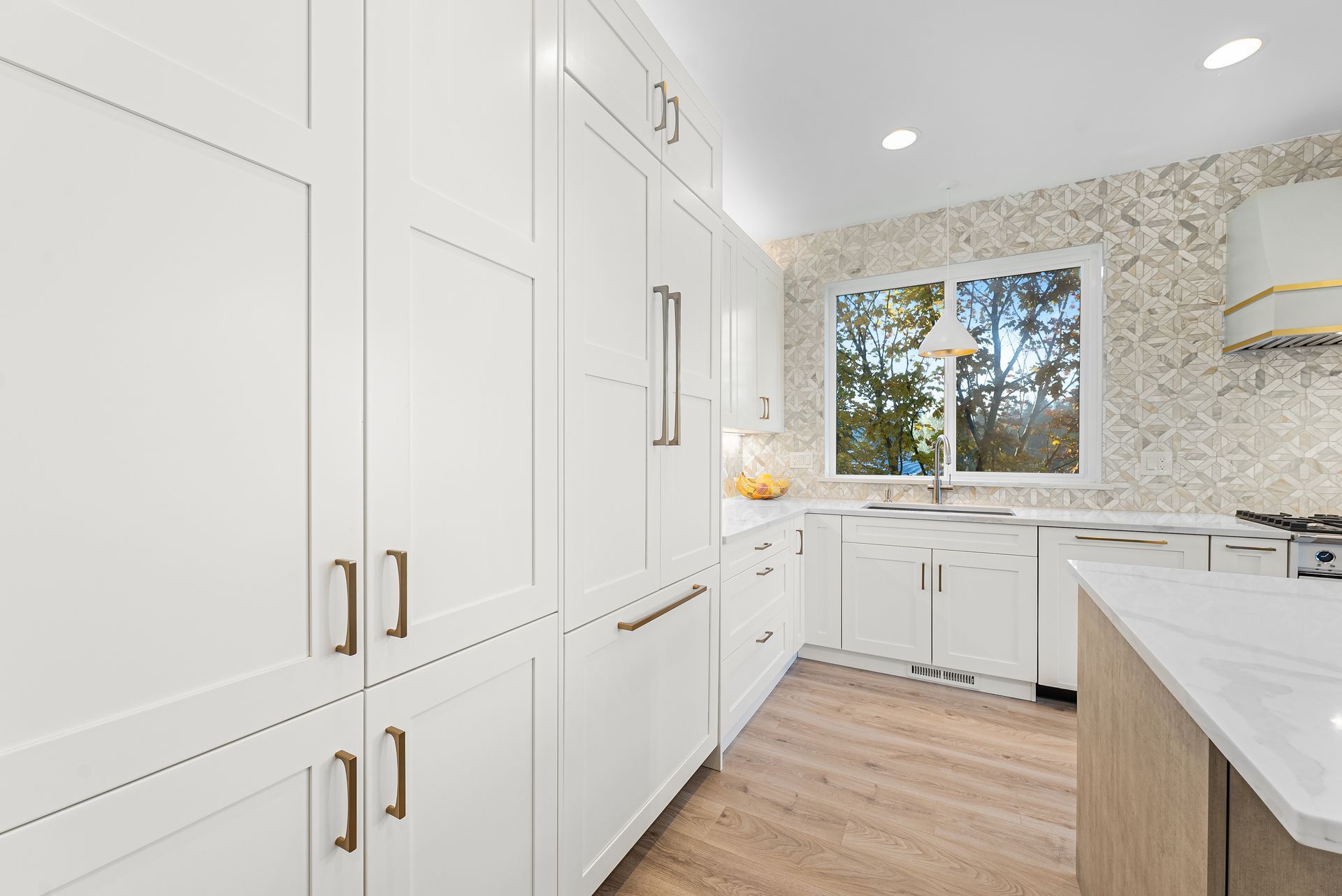 A kitchen with white cabinets and a large window.