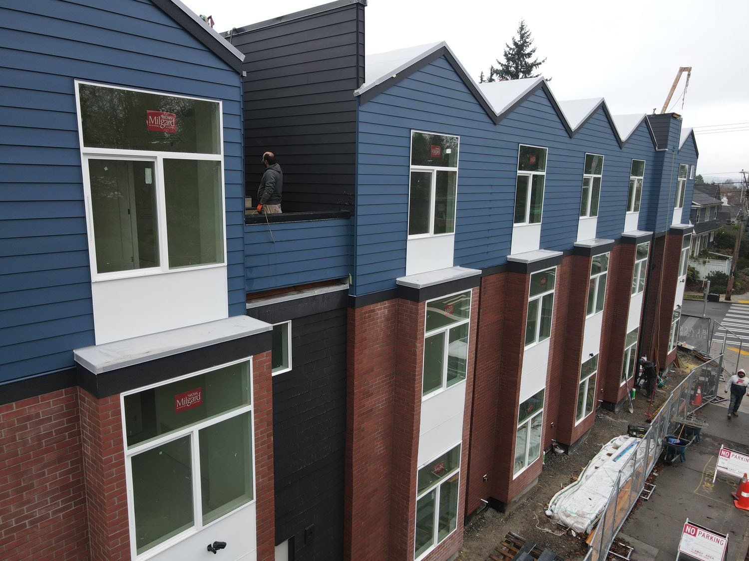 An aerial view of a row of houses with a man on the roof