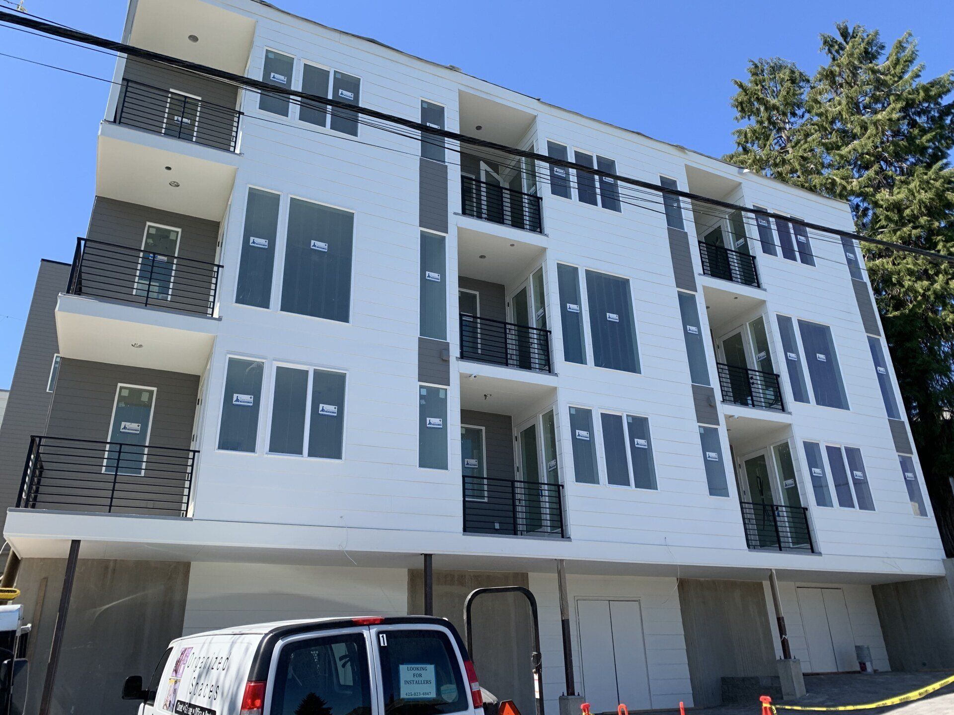 Modern white apartment building with balconies and a parked car in front