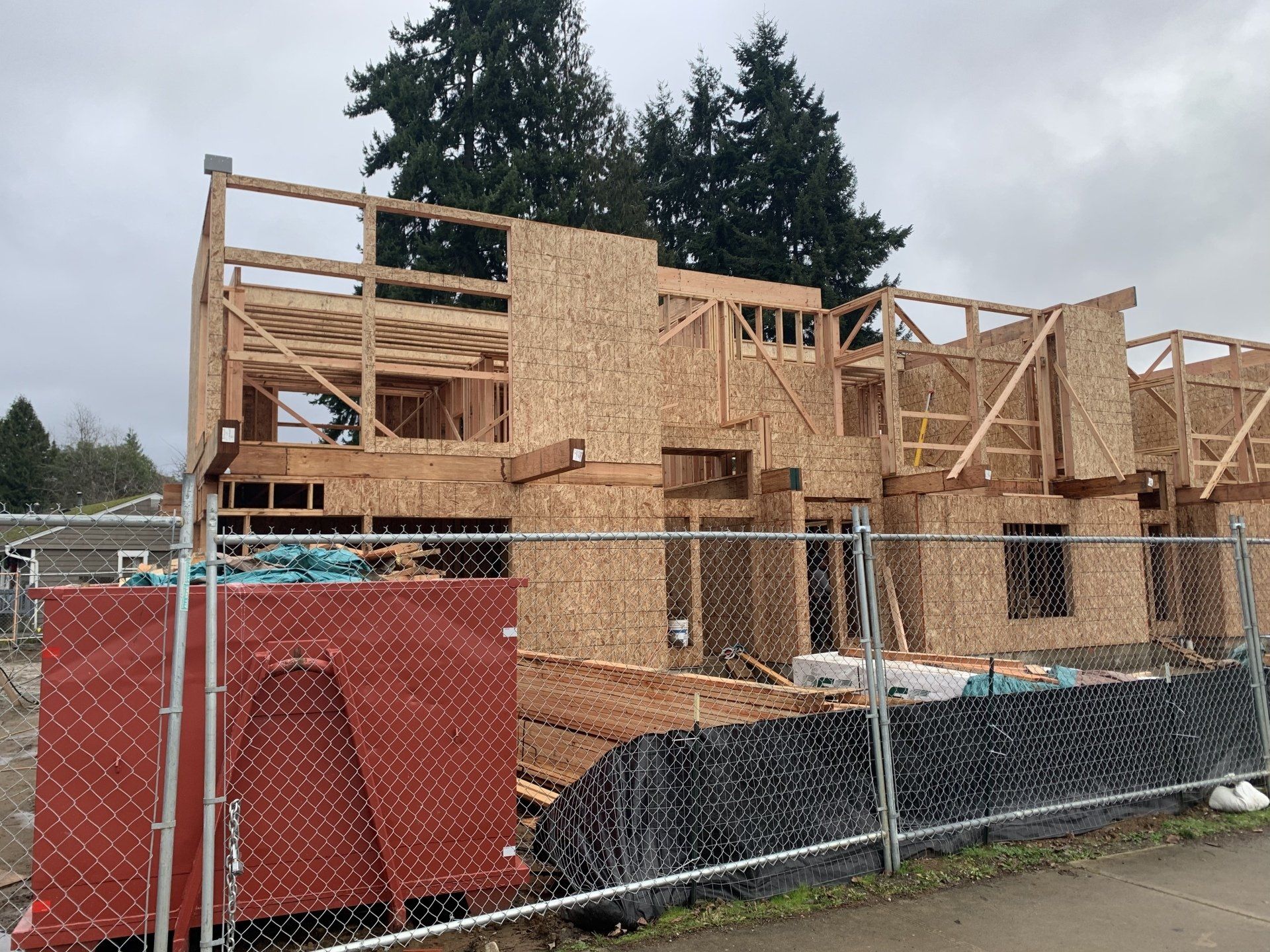 A house is being built behind a chain link fence.