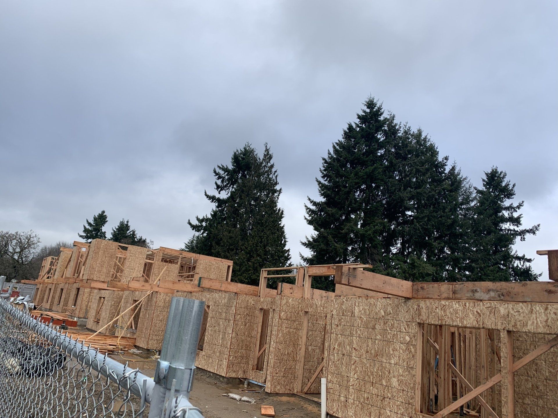 A building under construction with a fence and trees in the background.