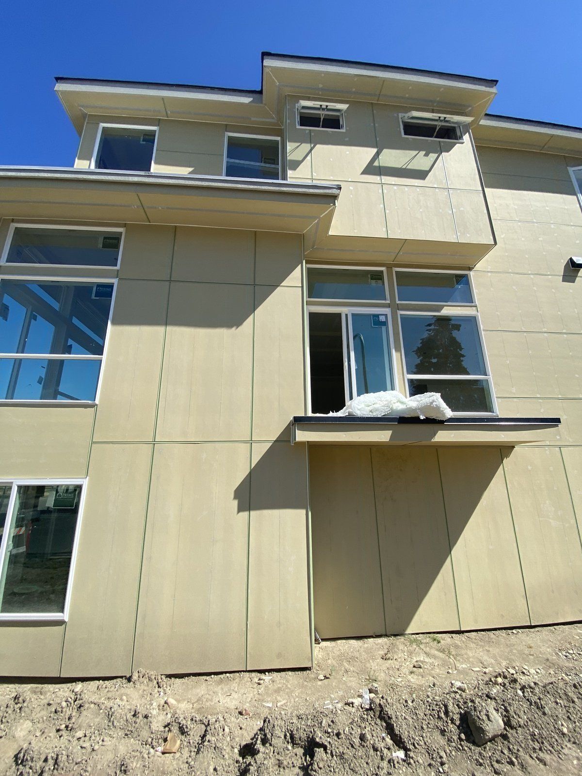 A large house with a lot of windows is sitting on top of a dirt hill.